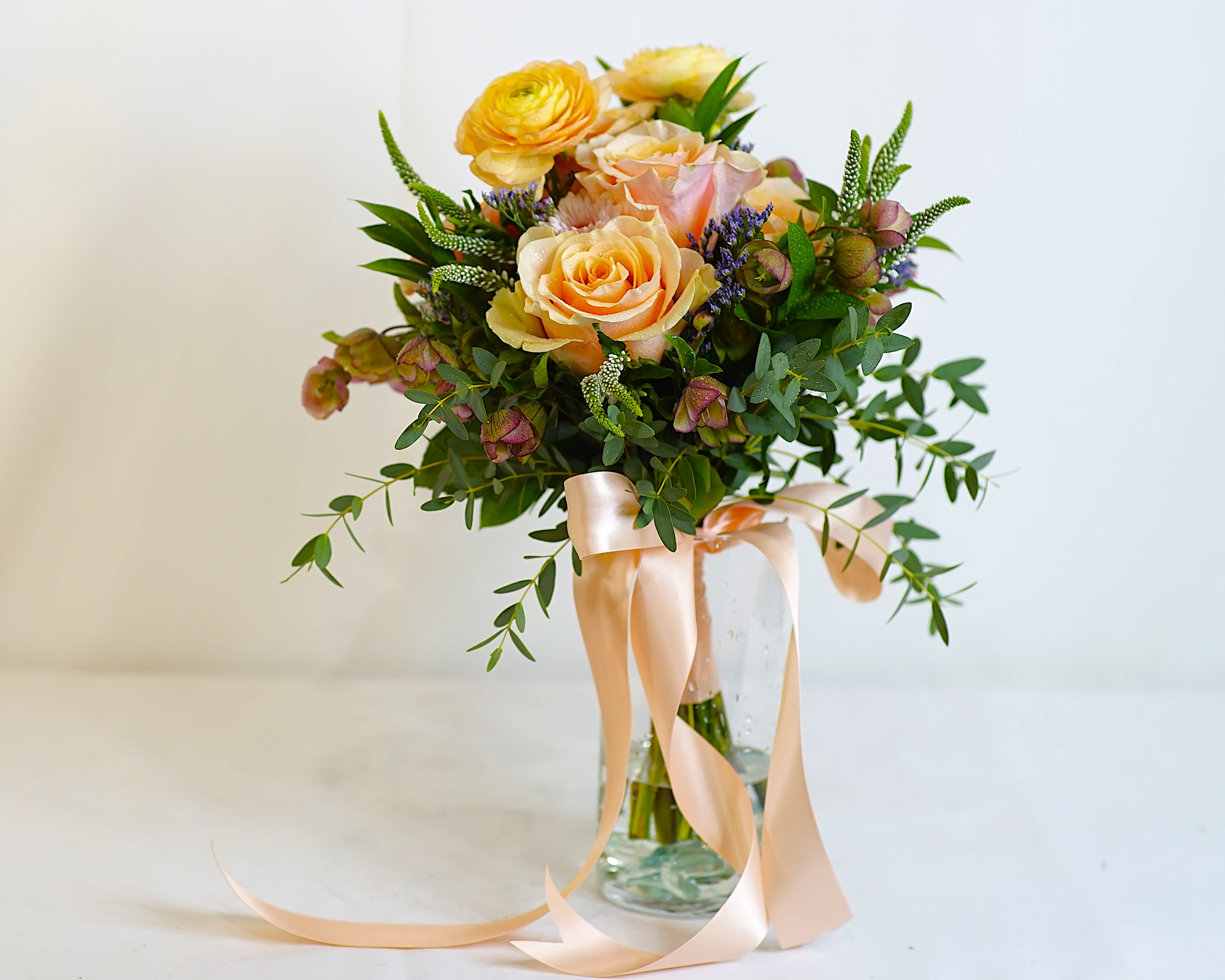 Love in Bloom - Ideal for brides seeking a romantic, garden-inspired aesthetic. This bridal bouquet captures the lightness of love and the beauty of new beginnings. Designed with a playful yet refined mix of pastel blooms and airy textures, this bouquet is perfect for spring and garden-style weddings. Its soft colors and delicate form create a dreamy, timeless feel.  Hand-tied wedding bouquet, finished with an ivory satin ribbon. Size: Approx. 8&quot;–10&quot; wide Color Palette: Pastel tones of blush, peach, yellow, lavender, and white