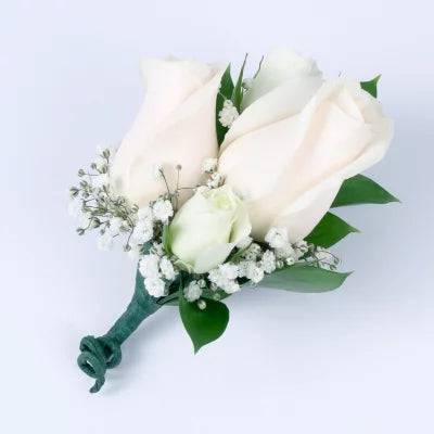 Double Rose Elegance Boutonniere WHITE - This elegant Double Rose Boutonniere features two roses set delicately against lush green foliage. This classic style radiates sophistication and provides a timeless look that is suitable for any formal occasion.