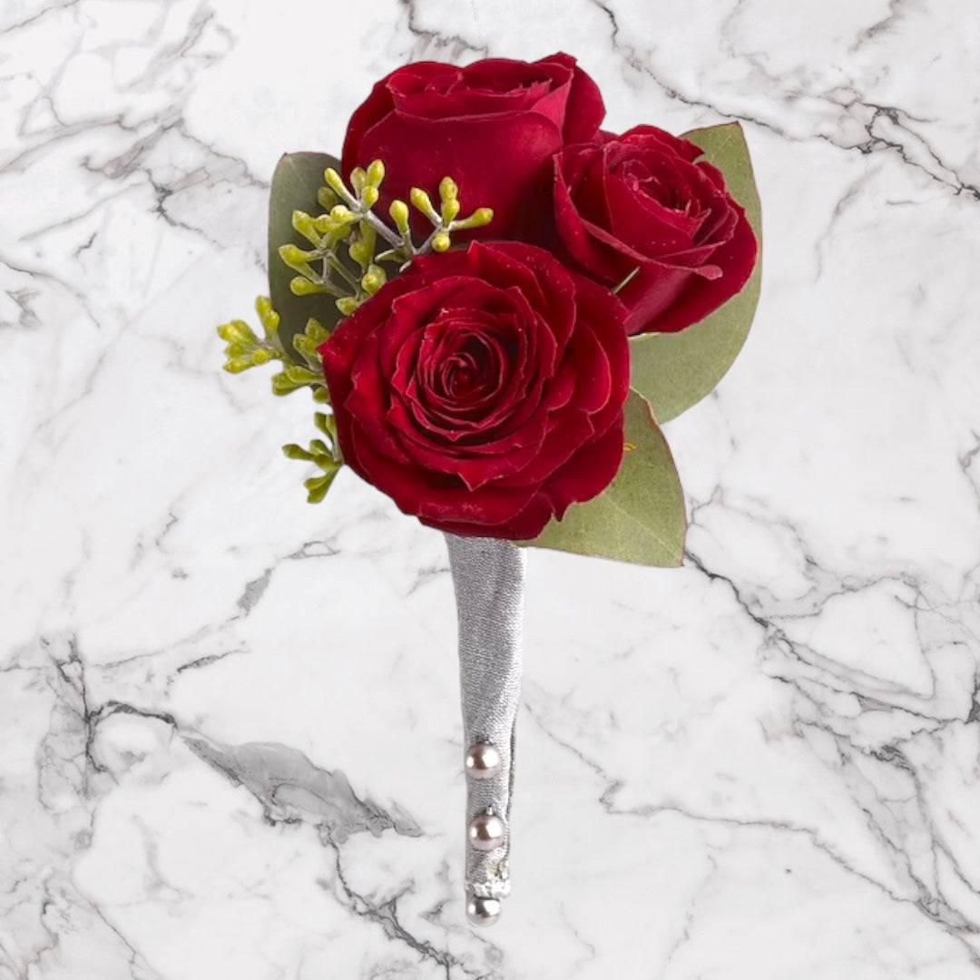 Elegant Spray Rose Boutonniere (RED) - Introducing our &quot;Spray Rose Elegance Boutonniere,&quot; a charming and timeless accessory designed to add a touch of sophistication to any special occasion. This boutonniere features a cluster of delicate spray roses, meticulously crafted to create a refined and elegant appearance.  Each spray rose in this boutonniere is chosen for its petite size and exquisite beauty. These miniature roses boast a stunning array of colors, from classic reds and romantic pinks to pristine whites and deep burgundies. Their dainty blooms are surrounded by lush greenery, enhancing their natural appeal.  The &quot;Spray Rose Elegance Boutonniere&quot; is a versatile choice, suitable for weddings, proms, anniversaries, and other formal events. Its compact design makes it a perfect fit for lapels, adding a touch of floral charm to the attire of gentlemen. Elevate your outfit with this exquisite Red Spray Rose Boutonniere from DGM Flowers | Fort Lauderdale Florist.