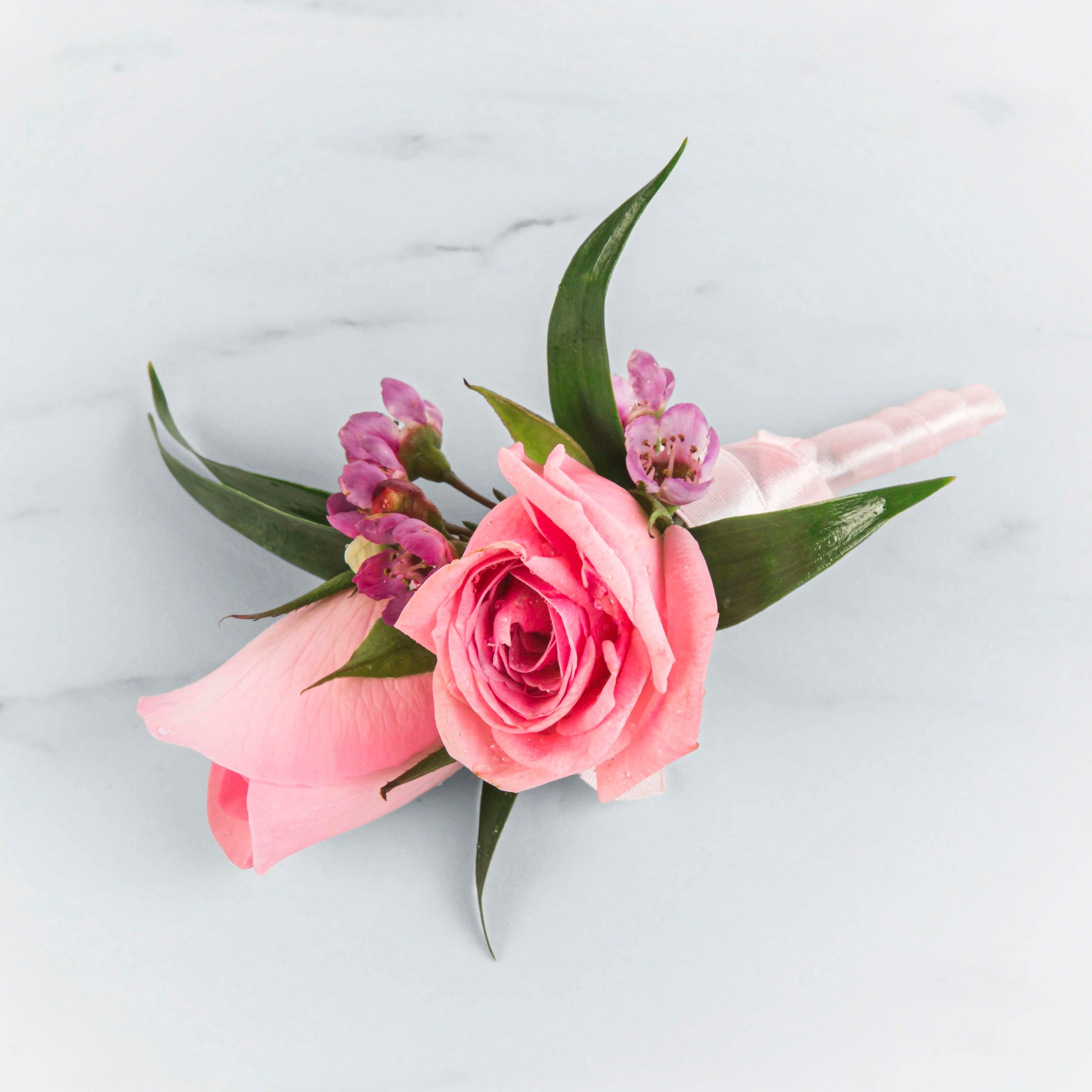 Pink Rose Boutonnierre - Introducing our &quot;Pink Rose Boutonniere,&quot; a dashing and romantic accessory designed to make a statement at your special occasion. This boutonniere features a cluster of exquisite pink spray roses, carefully arranged to exude charm and elegance.  The pink spray roses in this boutonniere are chosen for their delicate beauty and subtle fragrance. Each petite bloom adds a touch of romance and sophistication to your attire, making it the perfect choice for weddings, proms, and other formal events.  The compact size of the &quot;Pink Spray Rose Delight Boutonniere&quot; allows it to be effortlessly pinned to a lapel, tie, or shirt, enhancing your overall look with a subtle pop of color and fragrance. It's a symbol of love and admiration, making it an ideal choice for celebrating special moments with style.  Crafted with precision and attention to detail, this boutonniere captures the essence of floral elegance. It is a testament to the beauty of nature, encapsulated in a wearable work of art.  Elevate your attire and make a lasting impression with the enchanting &quot;Pink Spray Rose Delight Boutonniere&quot; from DGM Flowers. Embrace the allure of pink and let it accompany you on your unforgettable journey.