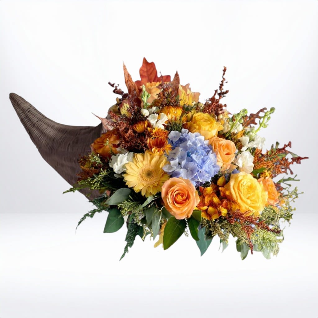 Autumn Sky Cornucopia - The Autumn Sky Cornucopia blends classic harvest tones with a touch of unexpected color. Featuring golden and peach roses, yellow gerbera daisies, orange mums, and soft blue hydrangea, this design is artfully arranged in a natural horn basket for a rustic yet elegant finish. A perfect Thanksgiving centerpiece or hostess gift, it celebrates gratitude and seasonal beauty.  Available for same-day flower delivery in Galveston, Houston, and surrounding areas, this design brings the beauty of fall gatherings to life.  Substitution Disclaimer: Due to seasonal availability, some blooms may be replaced with similar varieties of equal or greater value to maintain the design’s look and integrity. Your arrangement will always reflect the same spirit, palette, and premium quality.