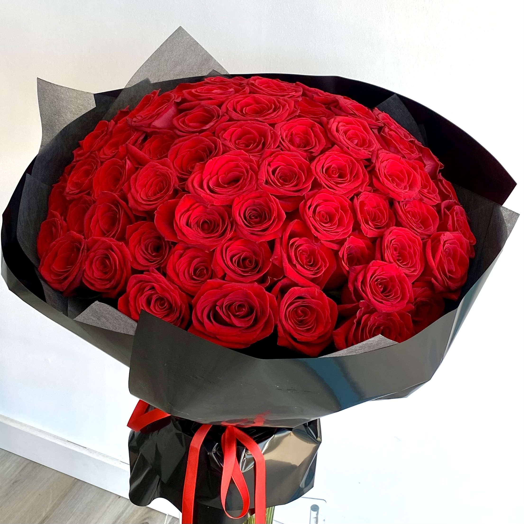 The Hundred Roses The Hundred Roses - A round bouquet of 100 red roses, wrapped in black paper. Flower types may vary depending on the season.