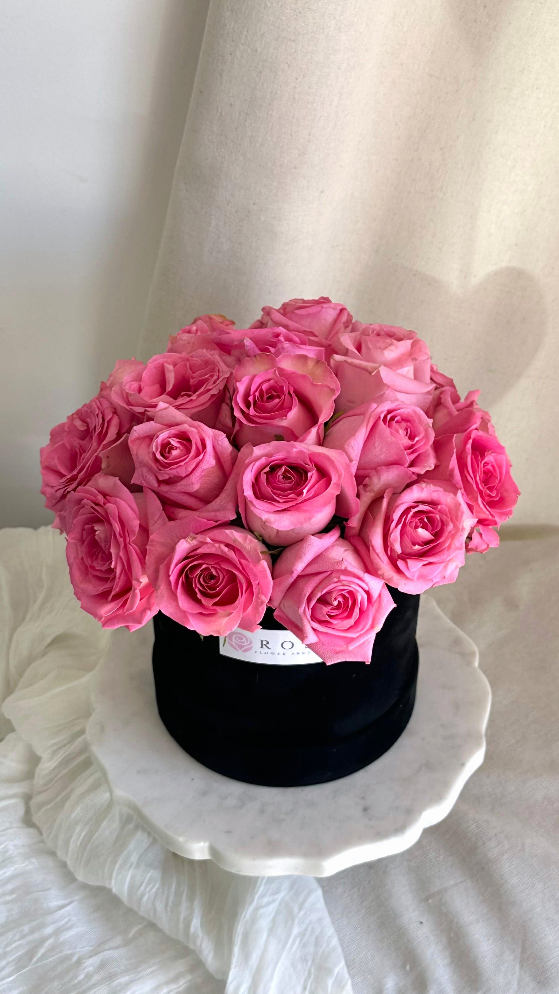 Love on Pink  - A medium round black velvet box with roses arranged in a dome shape.   Flower types may vary depending on the season.