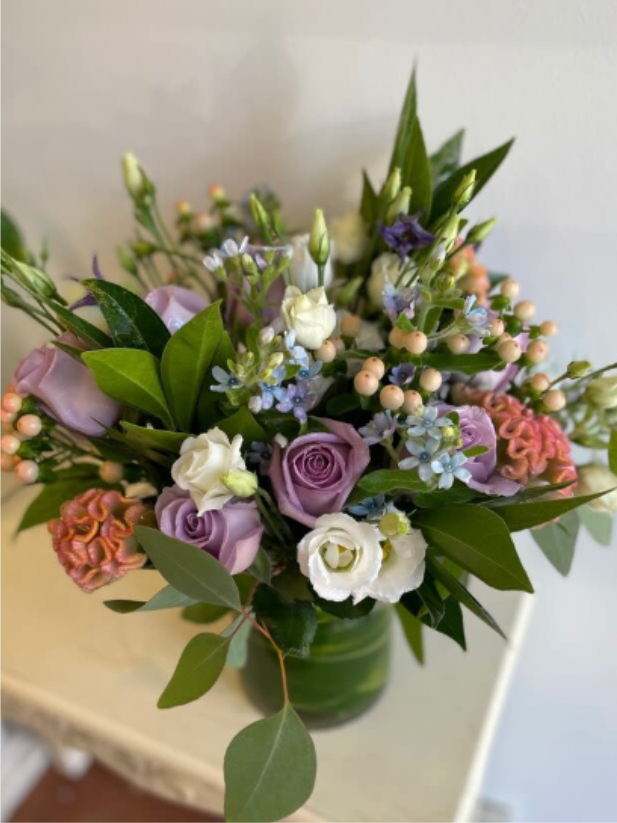 Winter 34 - Flowers mixed bouquet in a clear cylinder vase.   Tweedia, Lisianthus, Hypericum, Roses, Celosia, some greenery  *Depending on the availability, flowers might be substituted.