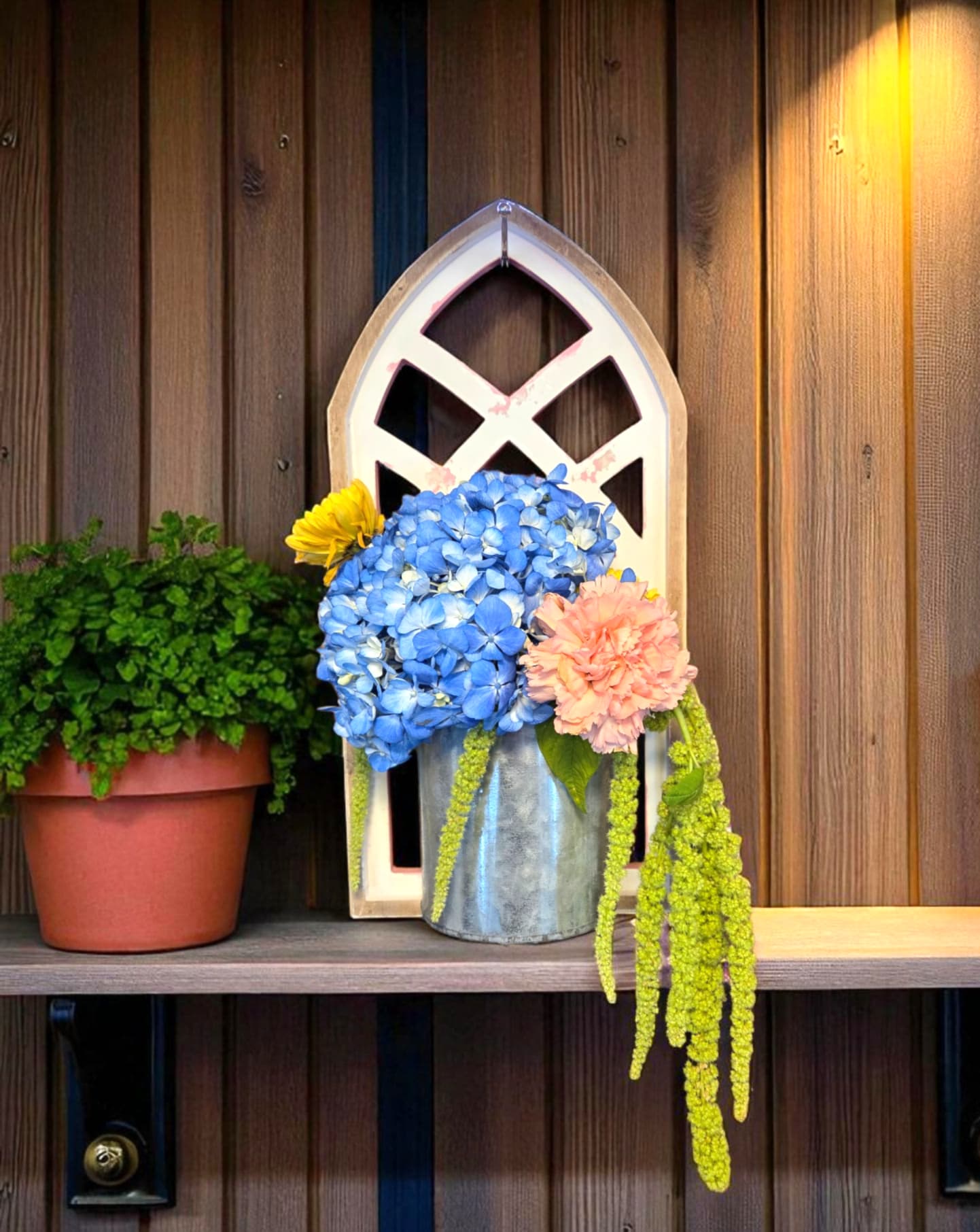 Rustic Arch - This distressed arch, with an elegant floral arrangement is perfect for the farmhouse or entryway. Hydrangea and hanging Amaranthus add a sophisticated look to a vintage piece. Say "welcome home" or simply "I care about you" with this charming arrangement. 