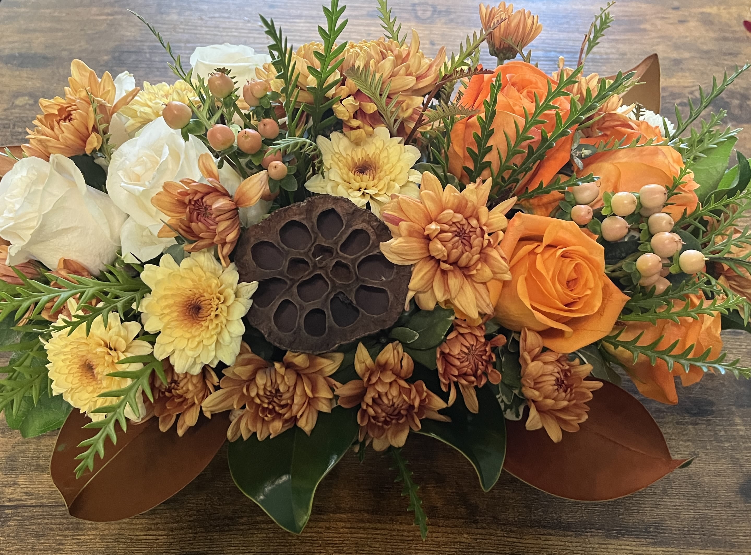 Golden Gratitude Centerpiece - Avail Thxgiving Week - Dramatic fall centerpiece of white roses, vibrant orange roses, fall accents and mums, lotus pod, magnolia leaves and a variety of eucalyptus.