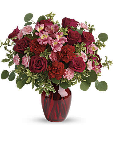 Blooming Belle's Bouquet - Tres belle! Ruby red roses and delicate pink alstroemeria are mixed with whimsical greens in a radiant vase for a beautifully blooming gift she'll never forget! Red roses, pink alstroemeria, red carnations, and pink miniature carnations are accented with silver dollar eucalyptus and pitta negra. Delivered in a ruby rose vase.