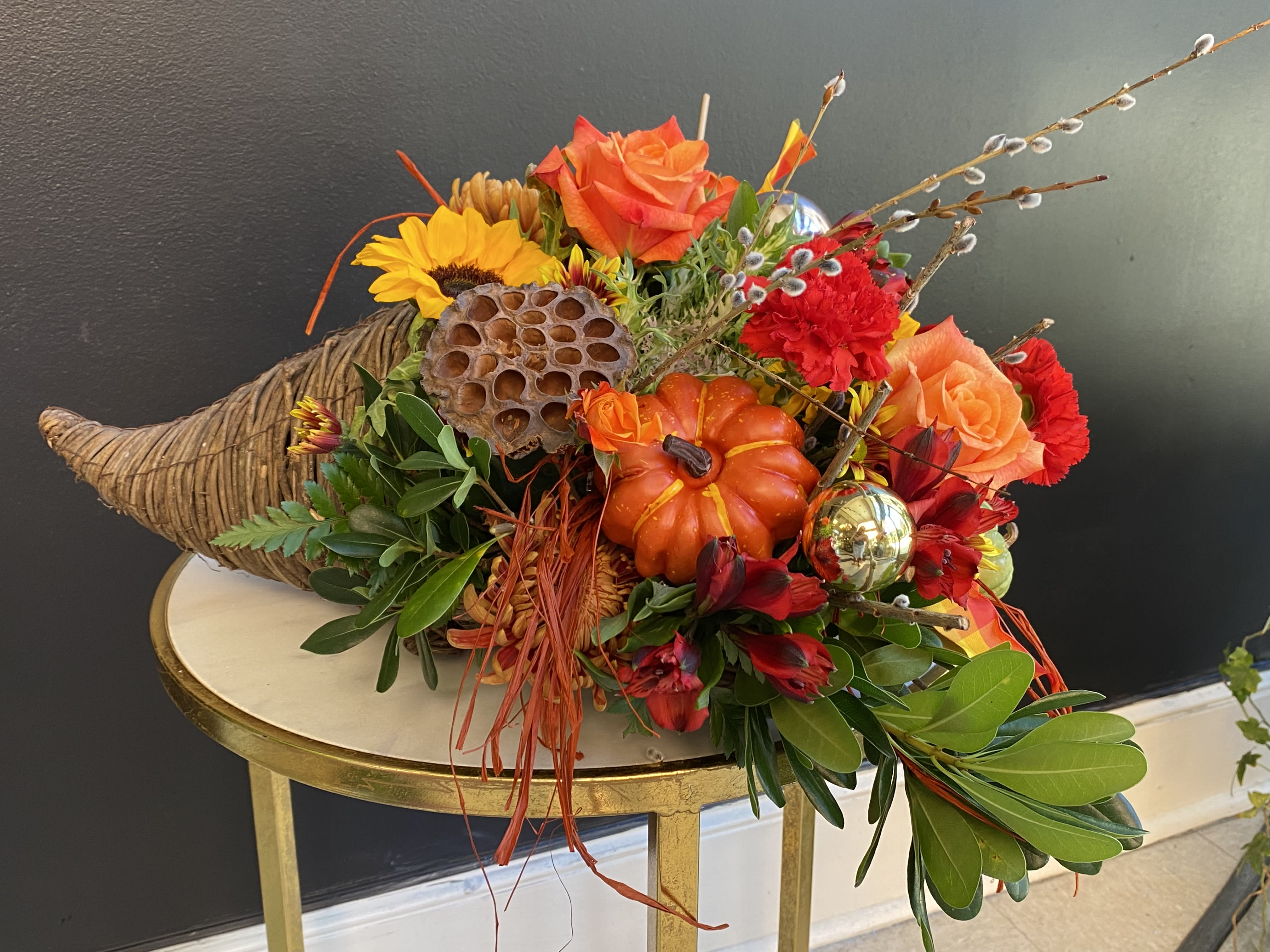 Thanksgiving Cornucopia  - Celebrate the season of Thanksgiving with this traditional symbol of autumnal abundance. The perfect Thanksgiving table decoration, this beautiful cornucopia is rendered as a horn-shaped wicker basket filled with fall flowers, wheat, and harvest accents. Also, ideal for the kitchen counter, coffee table or entryway. 