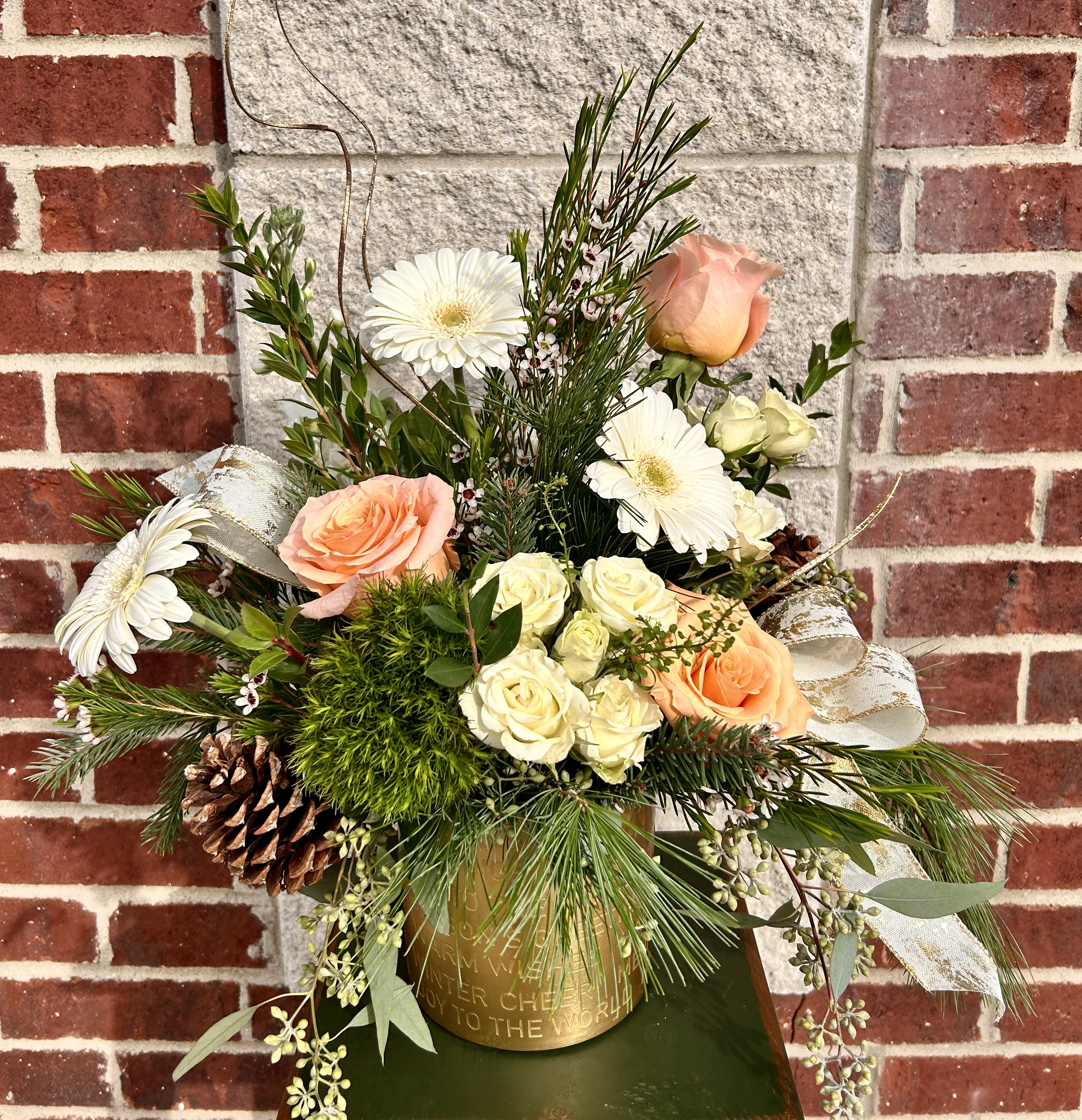 Warm Wishes - A unique combination of ivory, white and peach fresh flowers, evergreens, pinecones and beautiful ribbon are arranged in a 5x5&quot; brass pot that is embossed with holiday wishes. Flower varieties will vary based on inventory but color scheme will be the same.