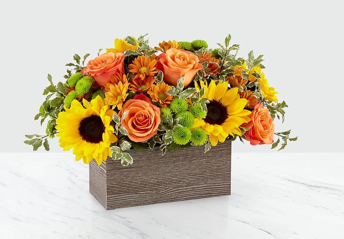 Happy Harvest Centerpiece - Savor the freshness of fall with the Happy Harvest Garden. Packed with a collection of orange roses, bright sunflowers and other seasonal blooms, this arrangement is a gorgeous gift for any occasion this Autumn. Whether it’s for an inviting centerpiece or festive décor in any room, these blooms are sure to bring smiles any time during the season.