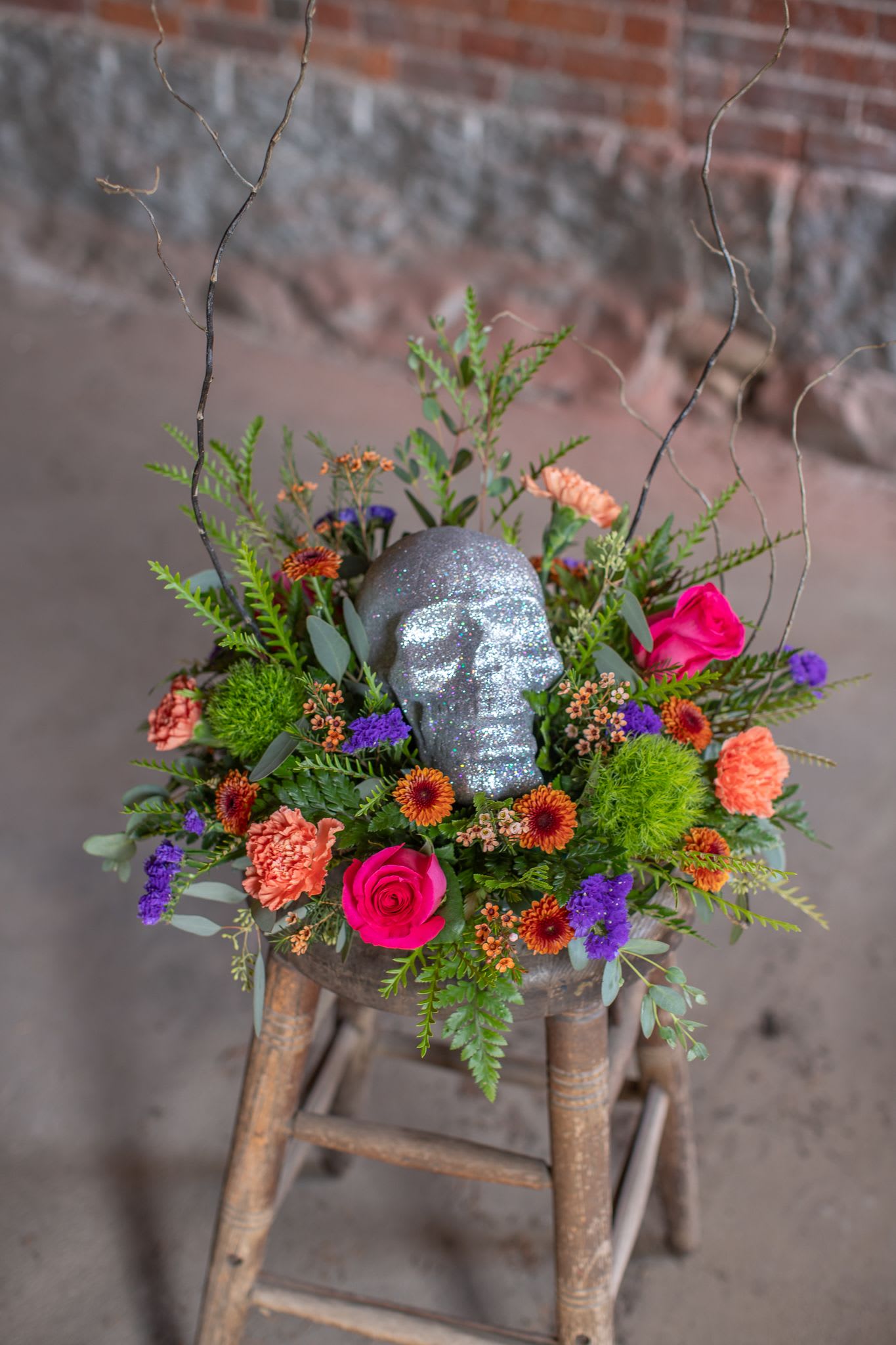 Sugar Skull - A sparkling sugar skull is a splendid addition to a Halloween themed centerpiece. Sparkle skulls are silver or green and perfect for your fright-fest or a friend who maybe a Halloween enthusiast. Flower varieties may vary from photo but colors will be orange, lime, purple and hot pink or red. Limited quantity available for October.