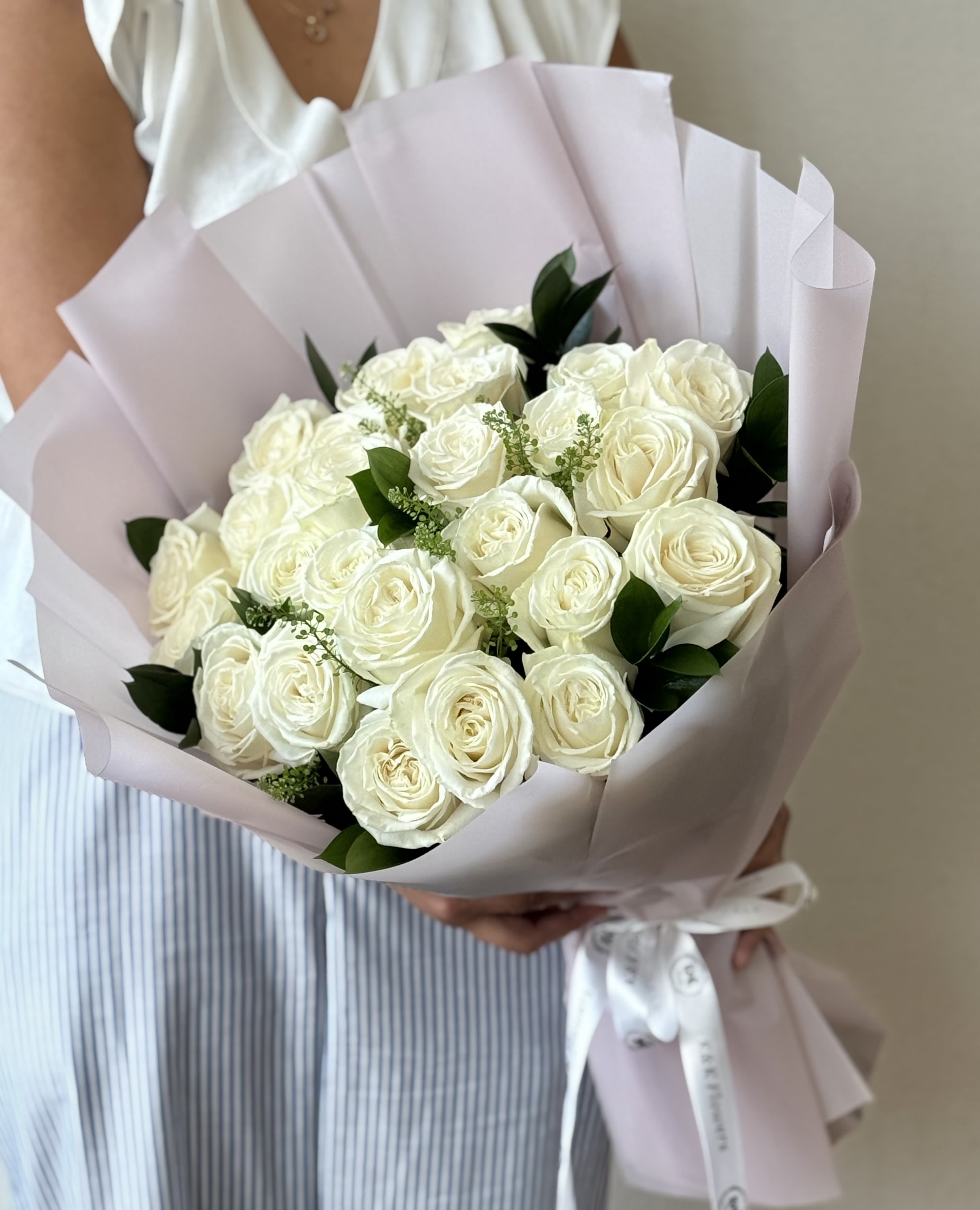 Two Dozen White roses - White Roses with greenery and decorative wrapping paper. All bouquets come without a vase; you can choose one in the add-on section.  Standard- 24 stems Deluxe- 50 stems Premium- 100 stems  Note: Flower food, transportation bag, and flower care instructions are included