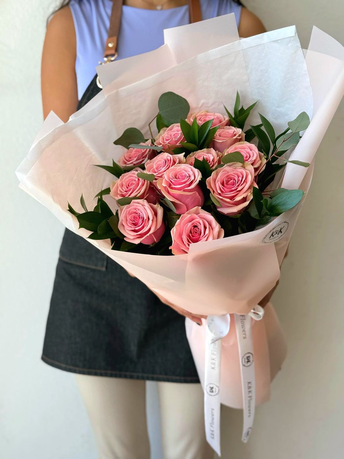 Dozen Pink Roses Bouquet - Dozen Pink Roses with greenery and decorative wrapping paper. All bouquets come without a vase. You can choose a vase in the add-on section  Note: Flower food, transportation bag, and flower care instructions are included