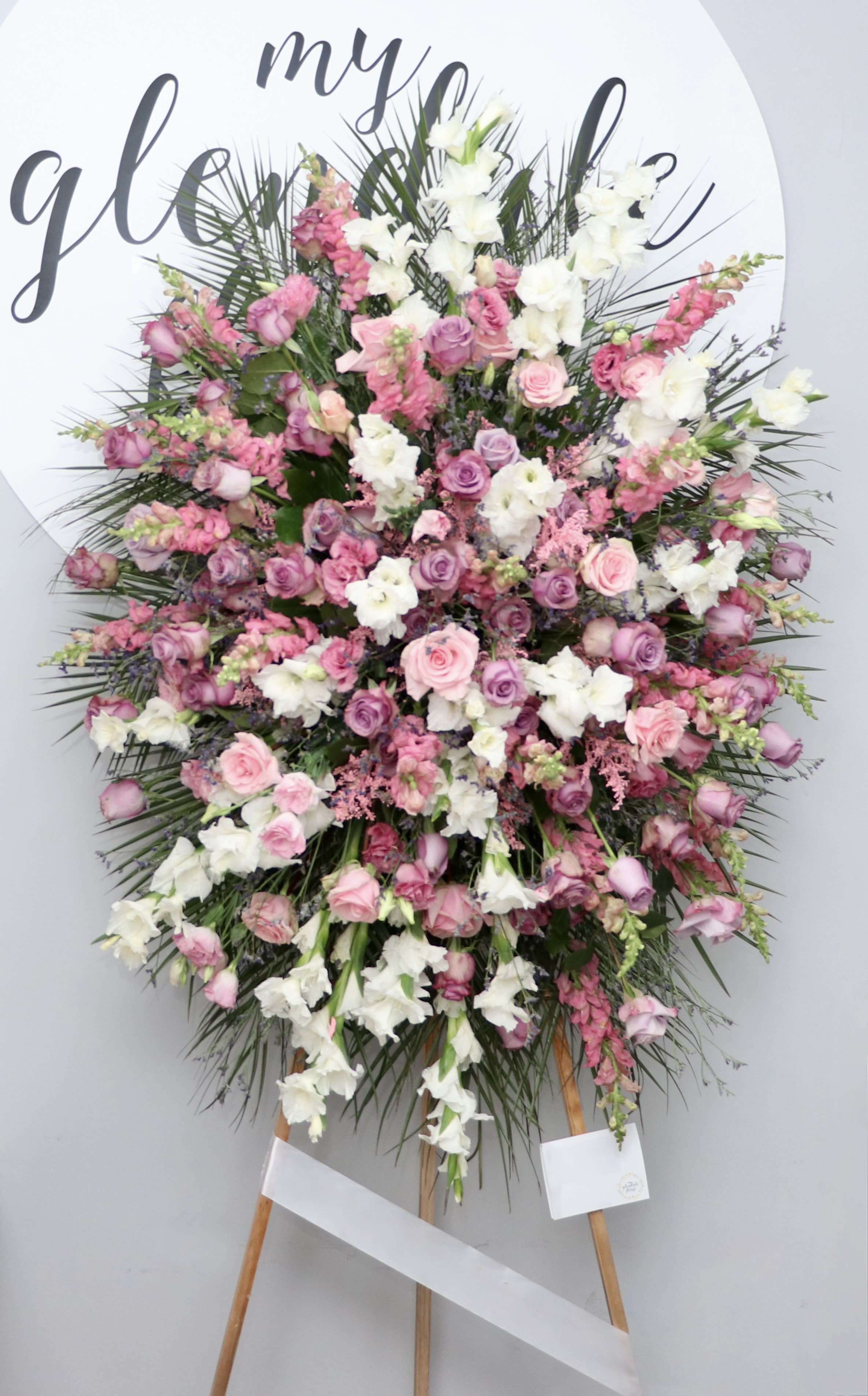 Petals of Peace  - This spray contains a collection of pink roses, white gladiolus, and bright pink snapdragons with seasonal greens.  We include easel, printed banner and delivery (some fees may apply). An additional banner can be added for $15.  Standard size is 30'' wide, deluxe is 36'', and premium is 42''.