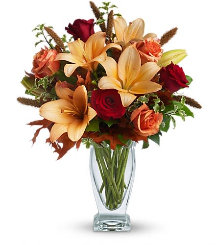 Teleflora's Fall Fantasia - Absolutely exquisite! This bouquet is a fall flower fantasy come true. All the richness of this colorful season is captured in a stylish glass vase. So pretty you might have to order one for a friend and one for yourself! Beautiful orange and red roses yellow asiatic lilies autumn oak leaves and more are beautifully arranged in an exclusive Couture Vase. Isn't fall fantastic?Approximately 17&quot; W x 20&quot; H Orientation: One-Sided As Shown : T167-1A