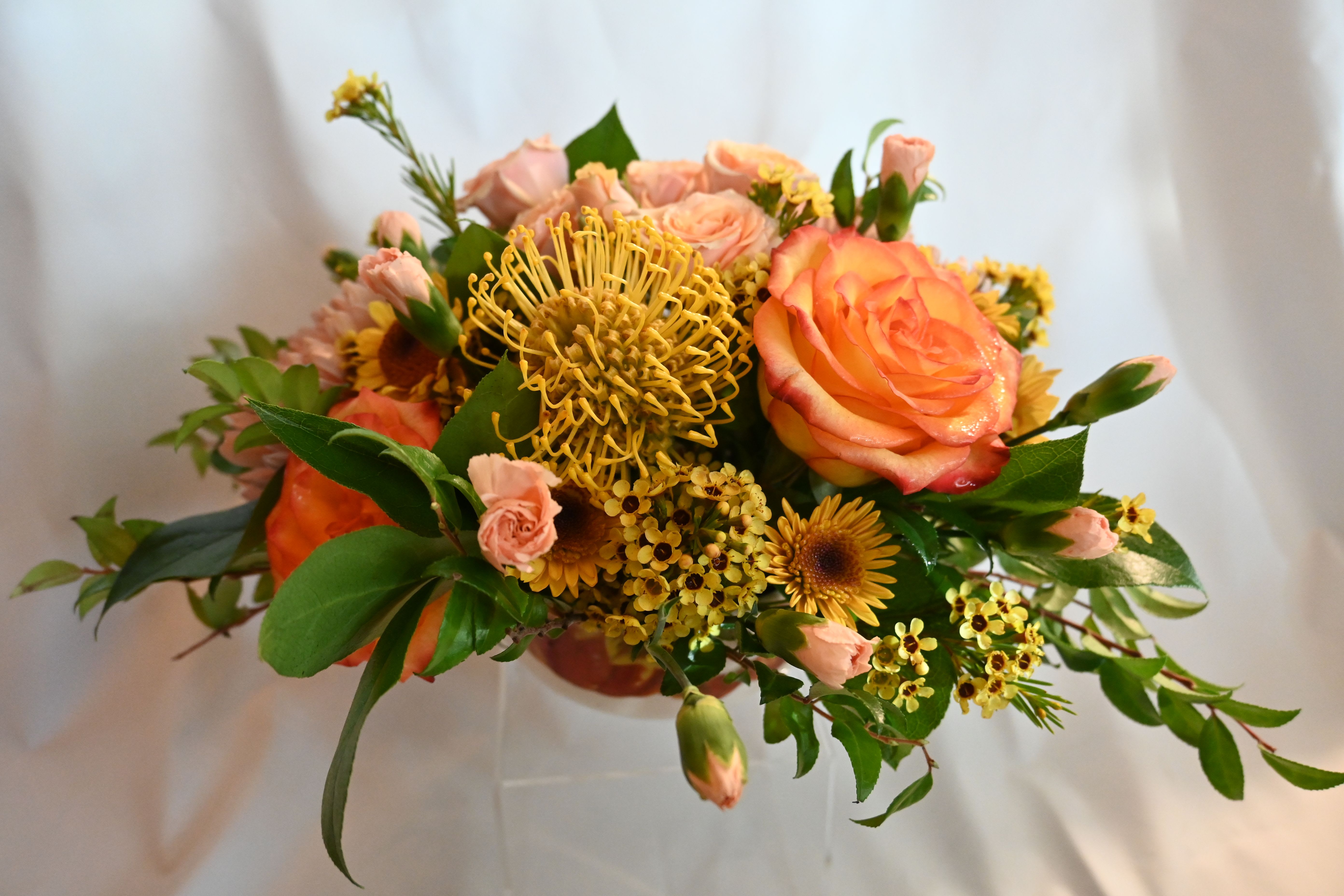 Designer's Choice Centerpiece: Standard - Celebrate the season with our Standard holiday centerpiece. Featuring seasonal blooms arranged with care, each design is unique and tailored to your occasion, using custom vessels and your preferred color palette. Perfect for Hanukkah, Christmas, Kwanzaa, Thanksgiving, or any festive gathering, this centerpiece adds holiday elegance.  AT CHECKOUT: Add special requests in the “special instructions” section. Specify: Preferred flowers?  Candles?  Shape &amp; style (tall/showy or low/lush)? AND occasion.   The image is for illustrative purposes ONLY. All Designer's Choice arrangements are one-of-a-kind and will vary in flower selection, color, and design to ensure freshness and creativity. While specific flowers can't be guaranteed, we promise a beautiful display.  DIMENSIONS: Approx. 18&quot; Across x 12&quot; Height