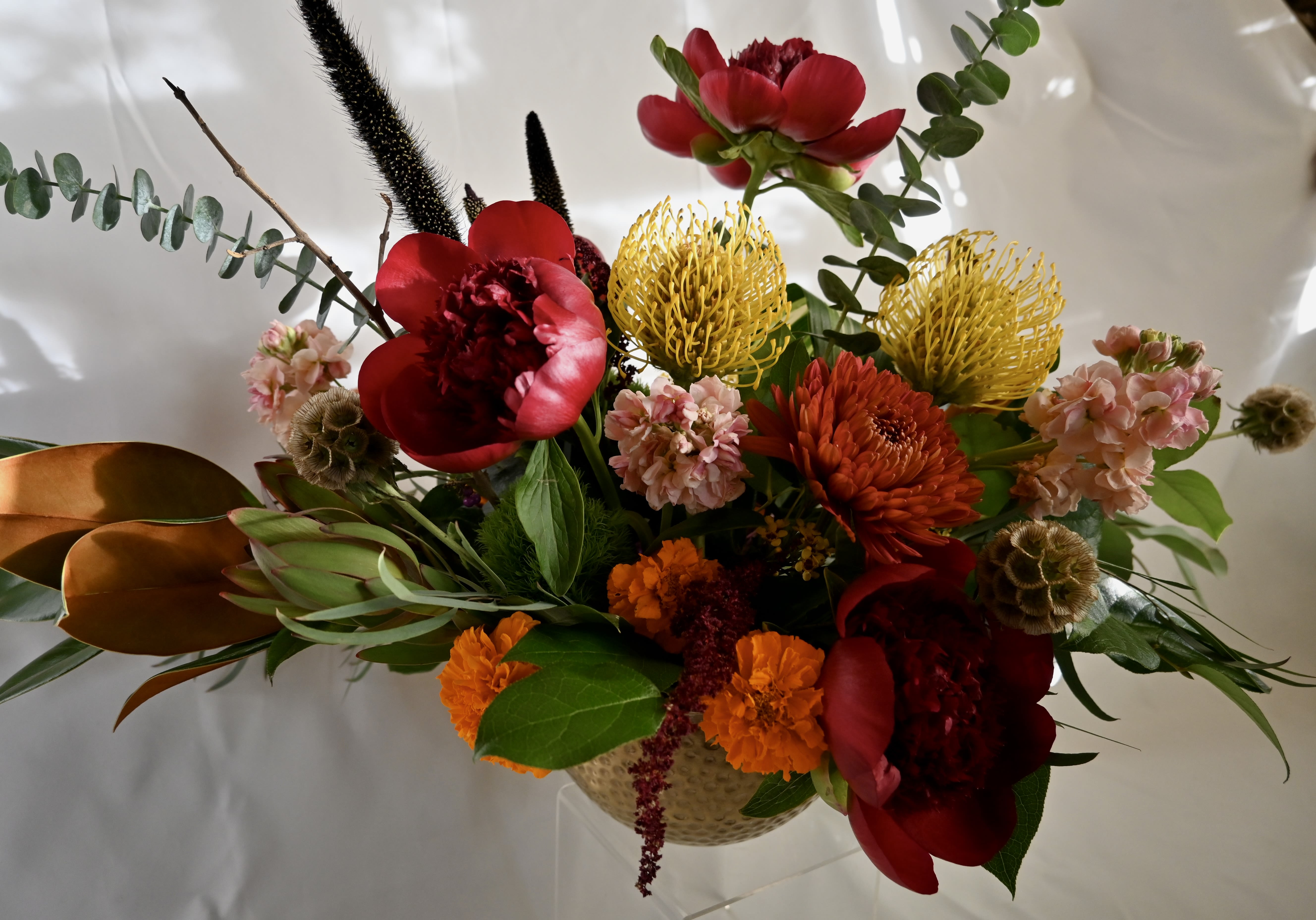 Designer's Choice Centerpiece: Premium  - Celebrate the season with our Premium holiday centerpieces. Each design features luxurious, premium blooms and fresh seasonal flowers. Our designers craft unique pieces tailored to your occasion, using custom vessels and your chosen color palette. Perfect for Thanksgiving, Hanukkah, Kwanzaa, Christmas, or any gathering, this centerpiece embodies holiday elegance.  At checkout: Add requests in the “special instructions” section. Please specify: -Preferred flowers -Shape and style (tall/showy or low/lush) -Occasion  While specific flowers can't be guaranteed, we promise a beautiful display. Photos are examples; exact flowers will vary.  DIMENSIONS: Approx. 30&quot; Across x 20&quot; Height