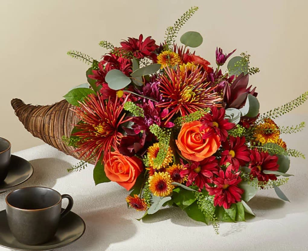 Autumn Herald Cornucopia - Celebrate everything you're thankful for with this iconic symbol of bounty and blessings resplendent with orange roses, bronze button pompons and more.