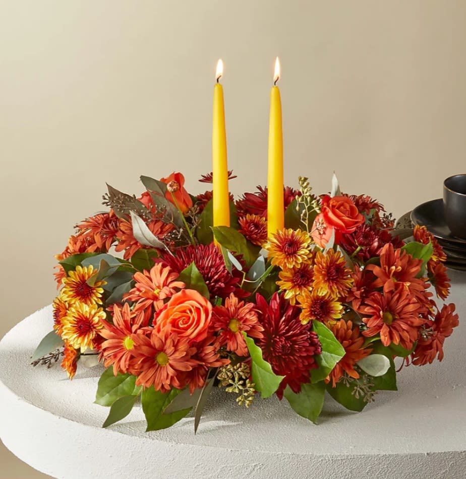 Ember Banquet Centerpiece  - Cast your holiday meals in a whole new light with this lovely centerpiece, which draws from the season's most stunning bronze, red and orange florals and foliage. 