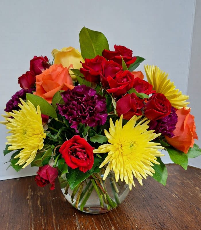 Mosaic - Globe vase with carnations, spider mums, spray roses and bright orange roses bring this arrangement together.