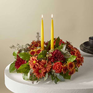 Burning Ember Centerpiece - Turn eating dinner into a dining experience. This charming centerpiece is filled with long lasting seasonal blooms in rich autumn tones. The addition of candles elevates this bouquet to a show stopping status. 