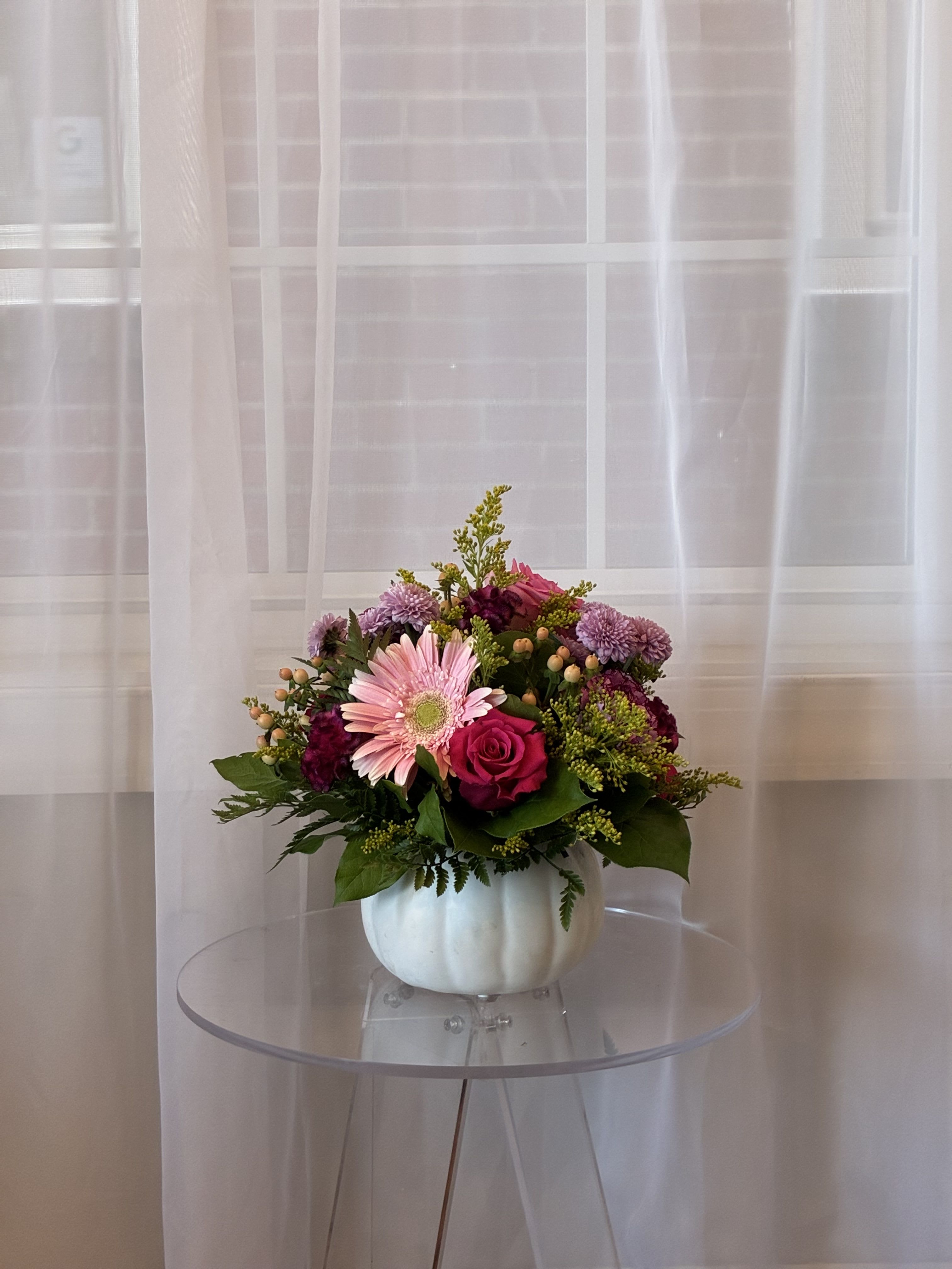 Gourd-geous Fall Blooms - Bring the magic of autumn indoors with our Gourd-geous Fall Blooms! This festive arrangement bursts with seasonal flowers and rich fall colors, all artfully designed in a whimsical Jack-o’-lantern vessel. Perfect as a centerpiece or a thoughtful gift, it combines the charm of harvest season with a playful Halloween touch.  Whether you’re celebrating the cozy glow of fall, hosting a festive gathering, or simply brightening your space, this arrangement is sure to be the gourd-geous highlight of the season.