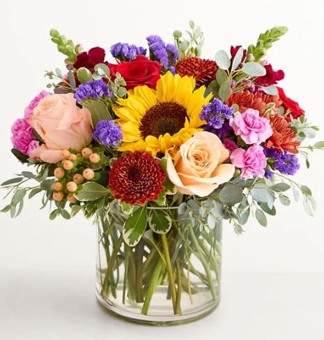Harvest Melody Bouquet - As bountiful as a robust autumn harvest, this bouquet is a dazzling celebration of the season. Our unique variety of astilbe finds itself in brilliant company: roses, sunflowers, snapdragons, and more. Arriving in a clear glass vase, this artful arrangement is a truly special gift to send to a truly special person.