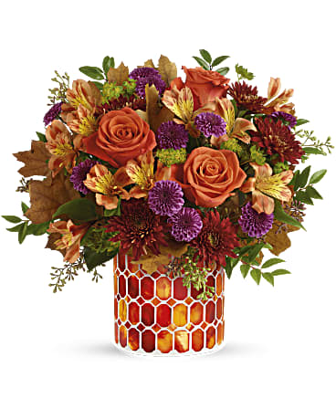  Color of  Sunset - This radiant arrangement includes orange roses, light orange alstroemeria, purple button spray chrysanthemums, burgundy cushion spray chrysanthemums, bupleurum, seeded eucalyptus and huckleberry, accented with transparent oak leaves.