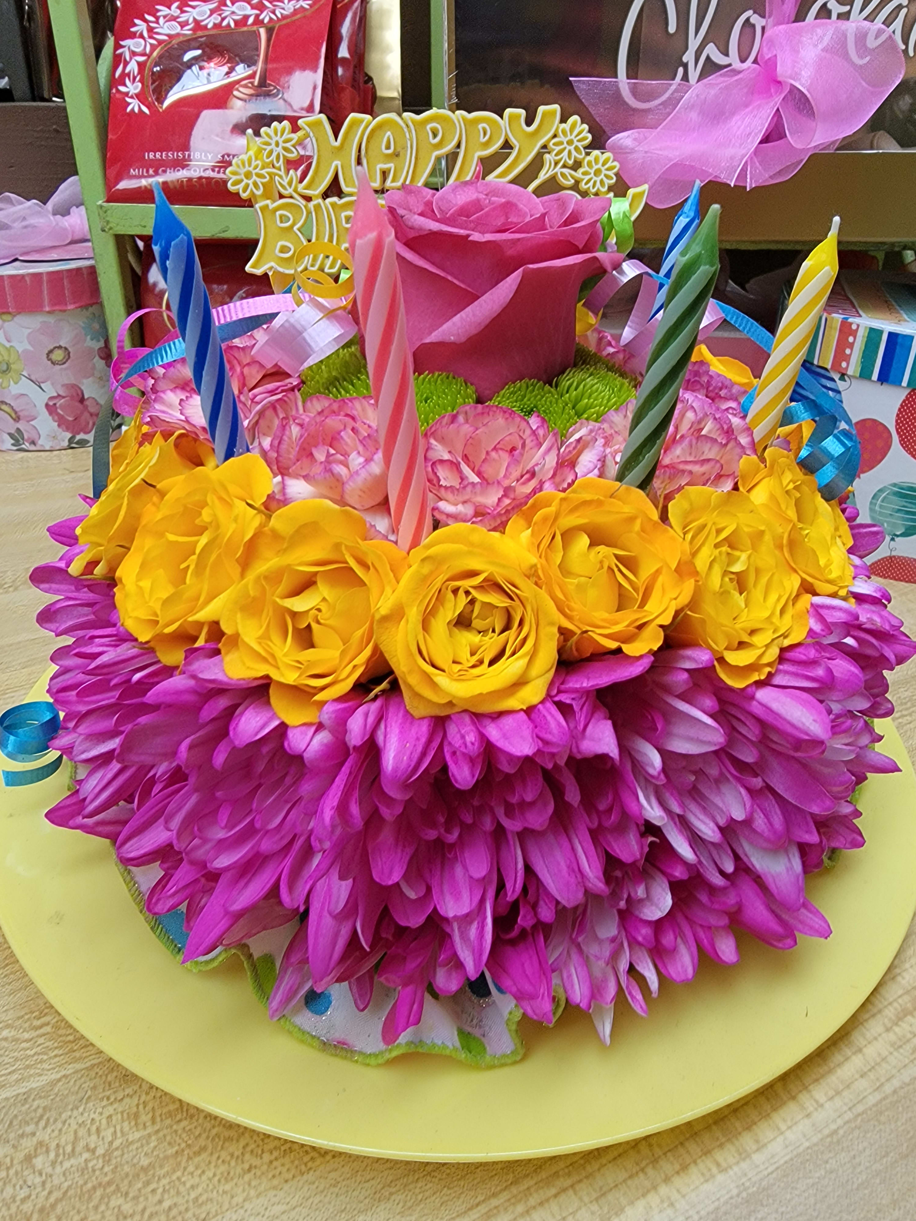 Blooming Birthday Cake - EXCLUSIVE If you want their birthday to be the brightest day of the year, your wish has come true! Our vibrant new flower cake has all the ingredients for a happy celebration. This confection-inspired creation is the perfect centerpiece for their party. Our florists hand-design each arrangement, so colors and varieties may vary due to availability. Dial up the fun by adding a balloon to your gift.