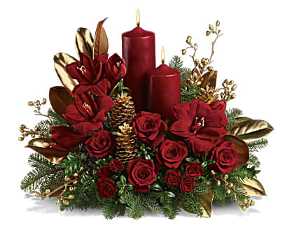 Candlelit Christmas - A striking seasonal statement for the dining table, hallway or entryway, this gorgeous arrangement is a festive mix of reds, golds and greens with two dramatic pillar candles for a warm glow. Luxurious red amaryllis and red roses are contrasted with fragrant noble fir and golden, glittering pinecones, magnolia leaves and berries. Two red pillar candles make this an ideal centerpiece and holiday decoration. Orientation: All-Around