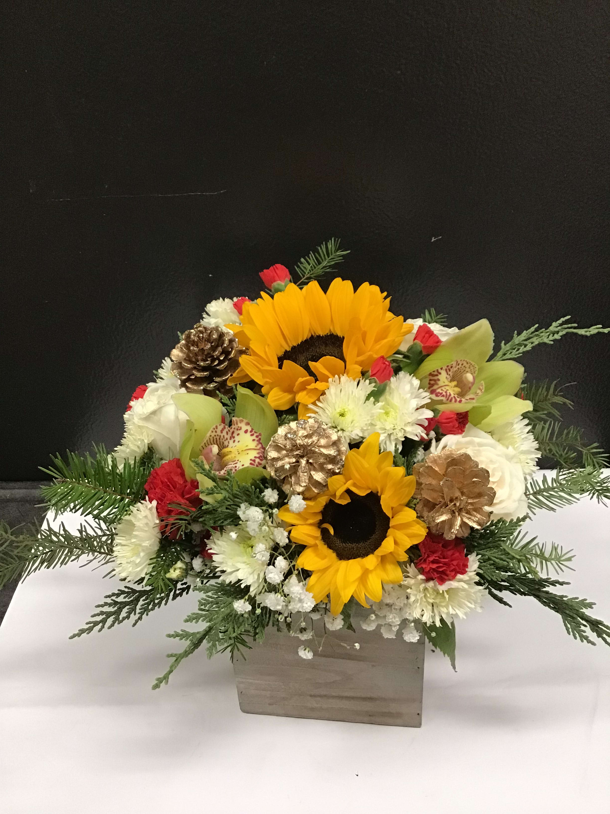 Winter Sunshine - This beautiful and warm  arrangement,  made with sunflowers, roses, orchid, pompom , and decorate with pinecone and seasonal greenery. This colorful arrangement is to bring some sunshine to someone during the cold winter. 