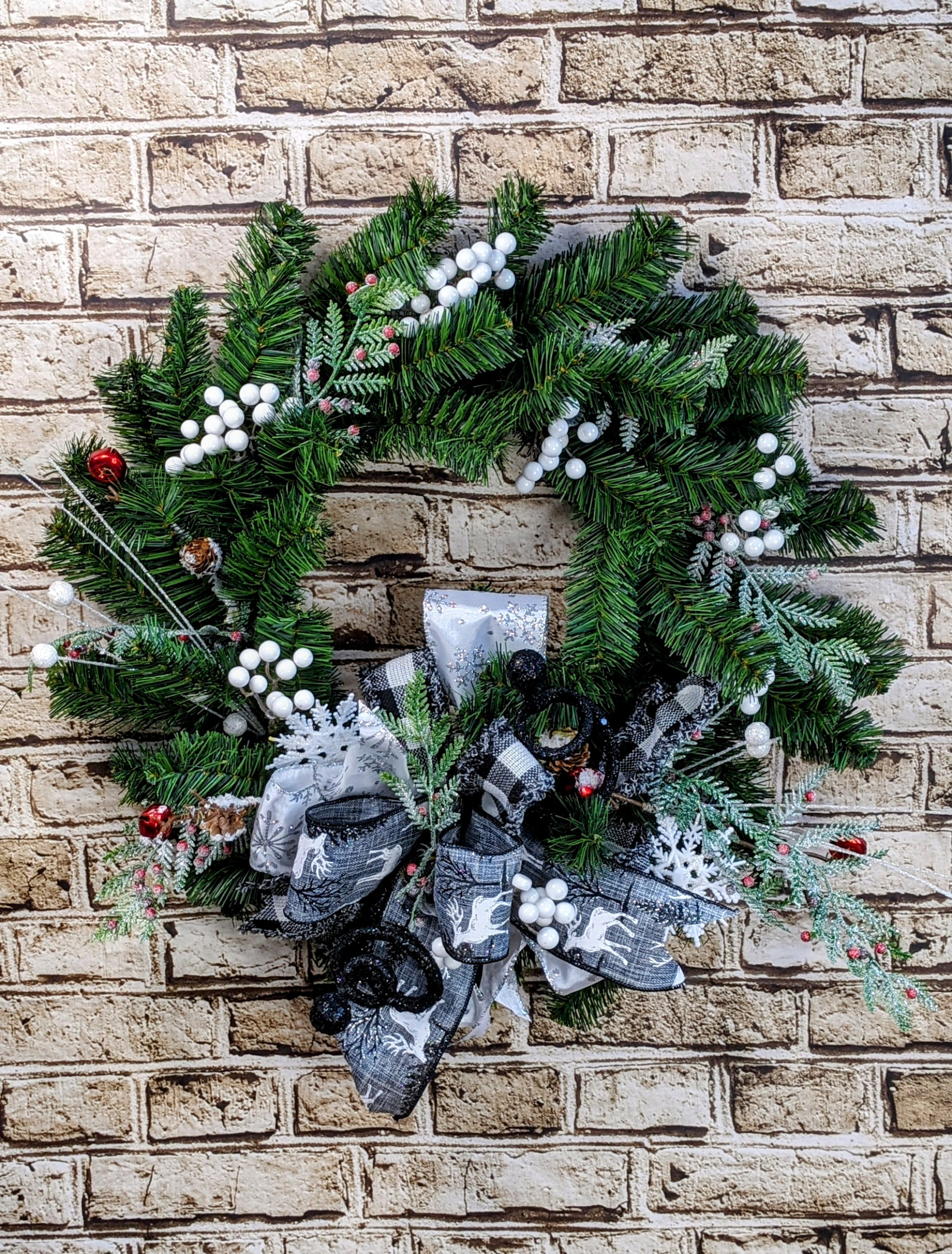 Elegant Black &amp; White Wreath - 18&quot; Artificial - An 18-inch artificial wreath that effortlessly blends elegance and holiday cheer. The lush greenery is highlighted with crisp white accents and subtle reds, creating a classic seasonal look. Black, silver, and white accents add a modern, sophisticated touch, while a coordinating ribbon ties the design together with style. This wreath is perfect for adding a festive yet refined touch to any door or wall this holiday season.  Approximate Dimensions: 18&quot; Diameter