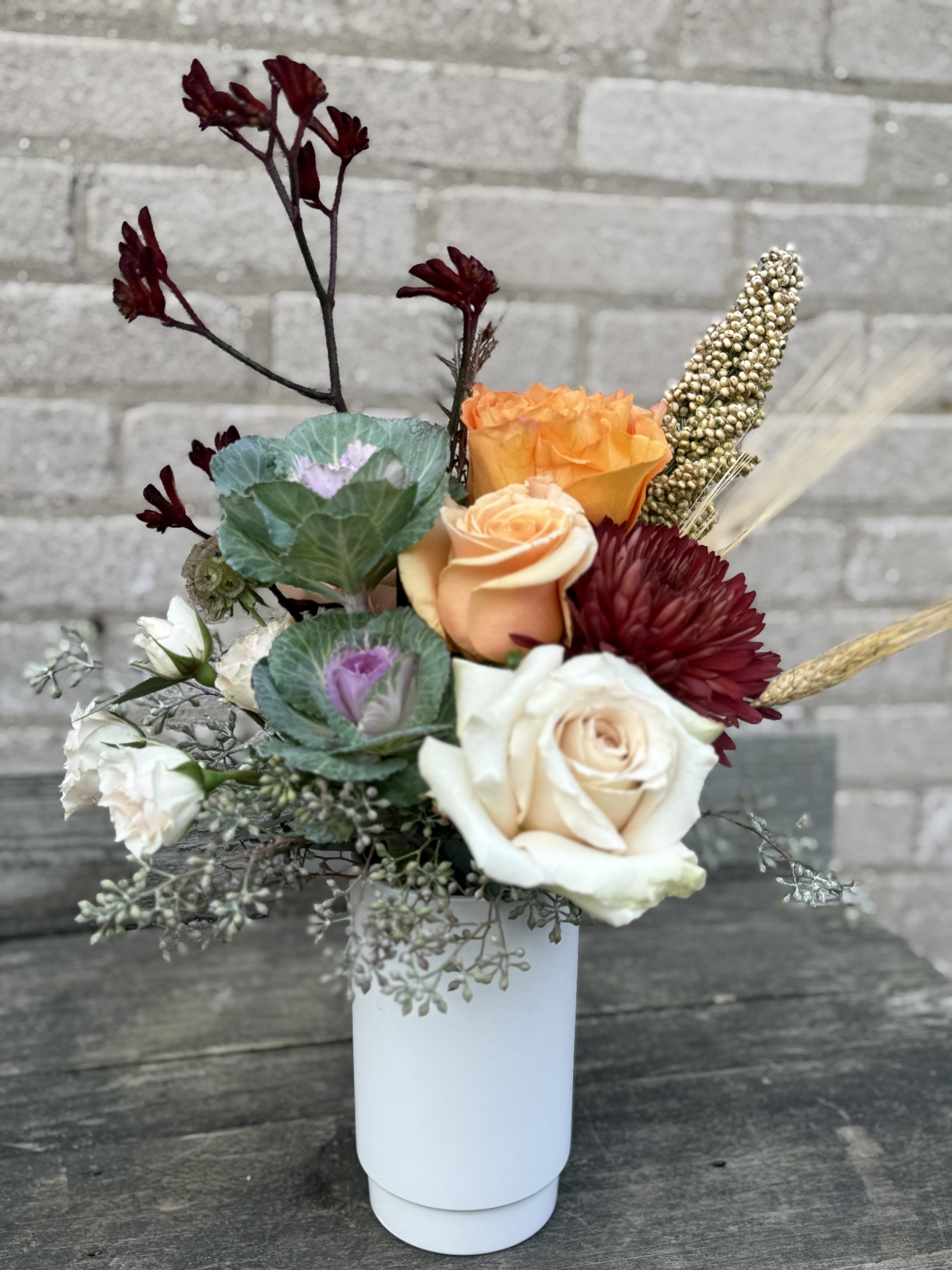 Shades of Autumn - An interesting design with fall colored blooms and greens. Perfect for a desk, hospital table or a hostess gift. Blooms may change as the season changes but will design as close to the picture as possible.