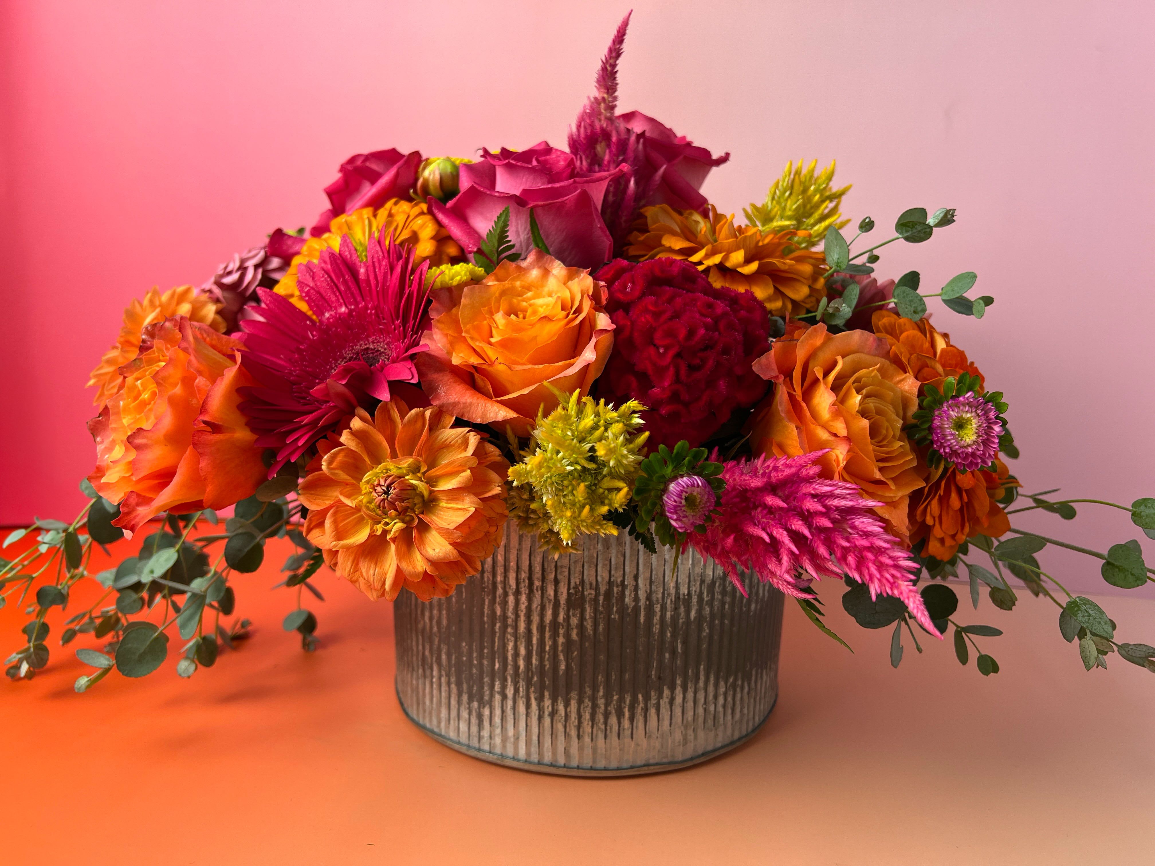 Amberfield Arrangement - Amberfield captures the vibrant beauty of nature in full bloom. Designed by The Flower Cart, your trusted Baltimore Florist, this rustic arrangement features a stunning mix of bright oranges, peaches, hot and soft pinks, yellow-greens, and lush foliage. Styled in a weathered gray corrugated metal vase, Amberfield blends modern farmhouse charm with radiant color and texture. Perfect for birthdays, celebrations, or simply adding warmth to your space. Order Amberfield today from The Flower Cart for same-day Flower Delivery in Baltimore and surrounding areas. Let our local floral designers bring fresh, handcrafted beauty right to your doorstep. 