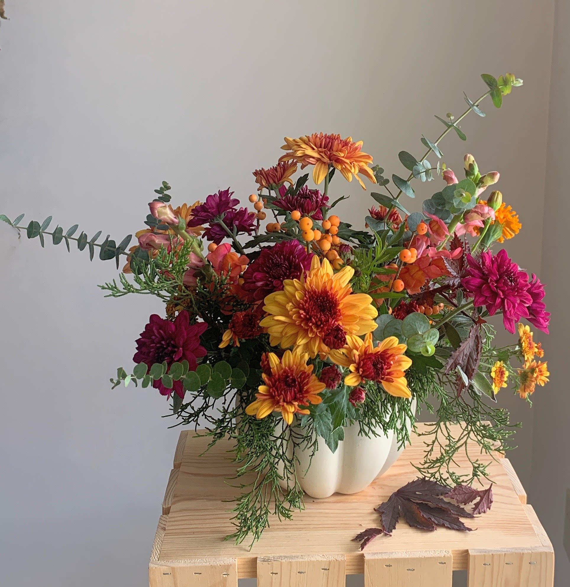 Thanksgiving Pumpkin  - Celebrate the season with locally sourced heirloom chrysanthemums, berries and fragrant greenery embellishing your table. Created in a ceramic white or deep bronze pumpkin this arrangement can be used as a table centerpiece or to share thoughts of Thanksgiving across the miles as a gift. 