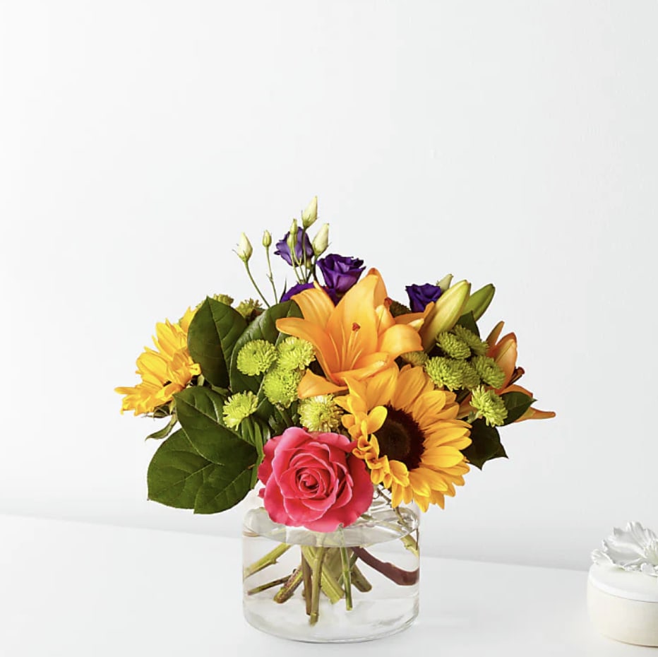 Golden Joy - Make this day their best day. Our local florist handcraft a colorful array of flowers in a clear glass vase to create a celebration in bloom. Perfect to give for a special reason or to simply share a smile.