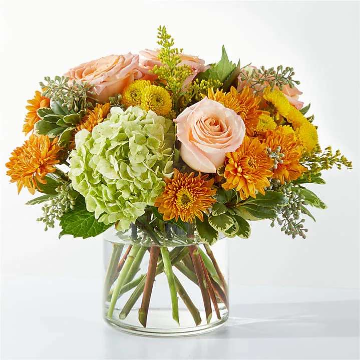 Warm Embrace – Cozy Autumn Bouquet - Soft hydrangeas, peach roses, and golden mums come together in a timeless glass vase — a warm blend of color and texture that captures the gentle beauty of autumn. Perfect for cozy homes or as a thoughtful gift that speaks from the heart. 