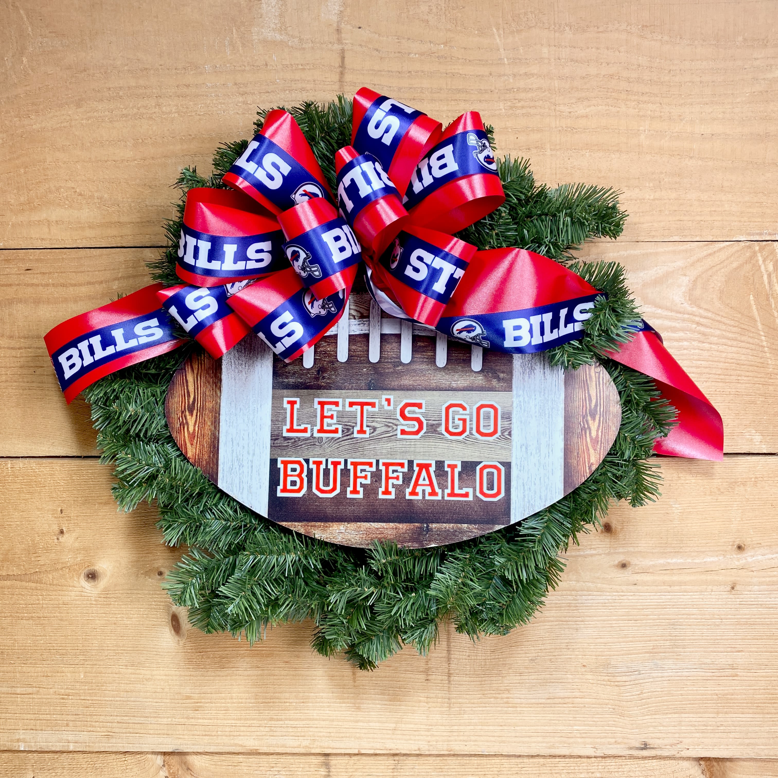 Let's Go Buffalo Wreath - Show off your team spirit this holiday season with our Let's Go Buffalo Wreath! This 20&quot; diameter wreath is made up of artificial greens adorned with a Bills themed bow and a football that says &quot;Let's Go Buffalo,&quot; making it the perfect decor for your home that can be packed away and cherished for many years to come!