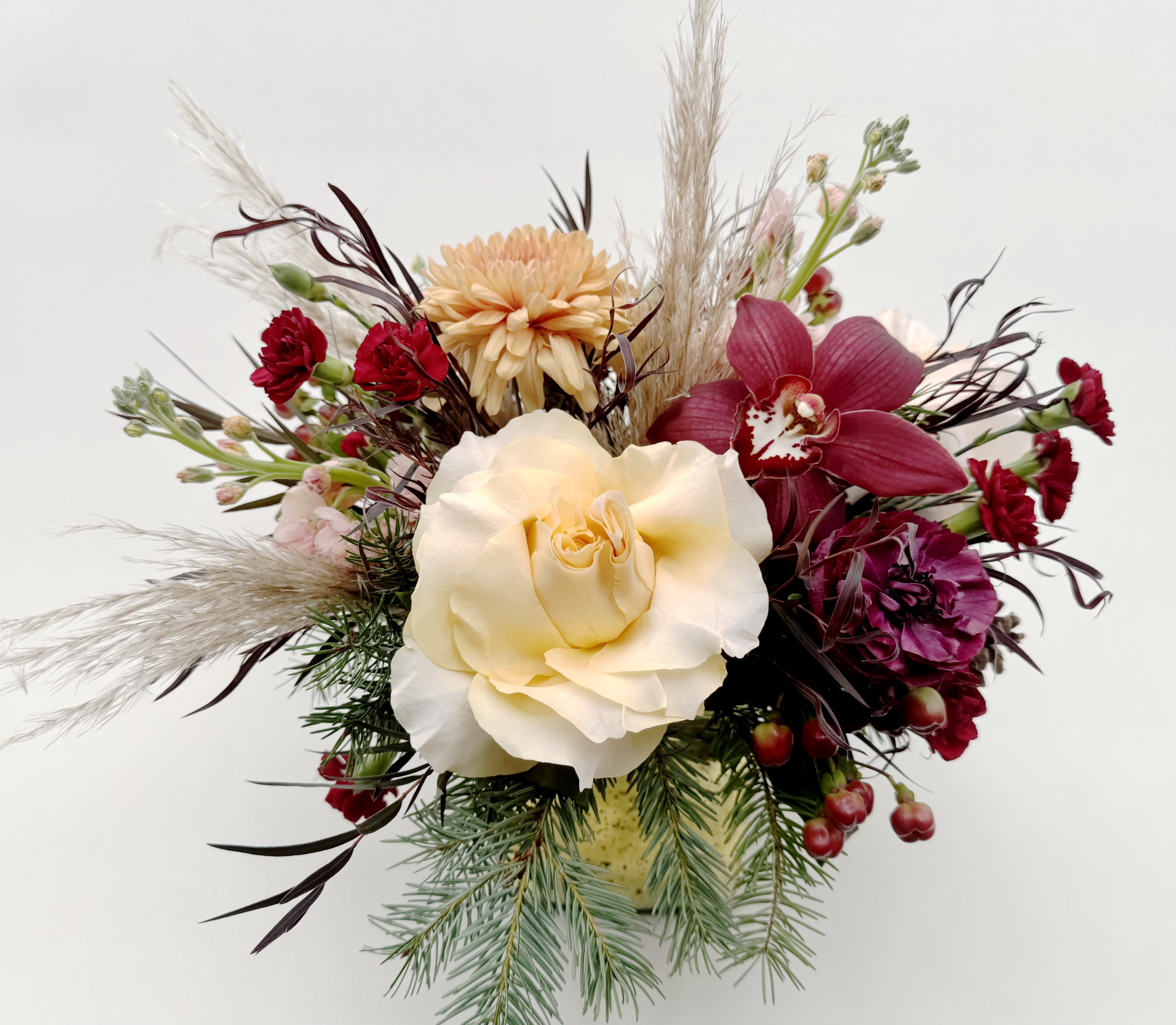 Sexy Christmas  - Make it a Sexy Christmas this year! Our Sexy Christmas arrangement has pine cones, winter greens, sultry burgundy, and pinky peach flowers that are arranged in a gold mercury glass cube vase.   Delivery Info- We make all of our deliveries after 1pm every day. If the weather is very cold, we prefer not to leave the flowers outside. Please let the recipient know that they should expect delivery.