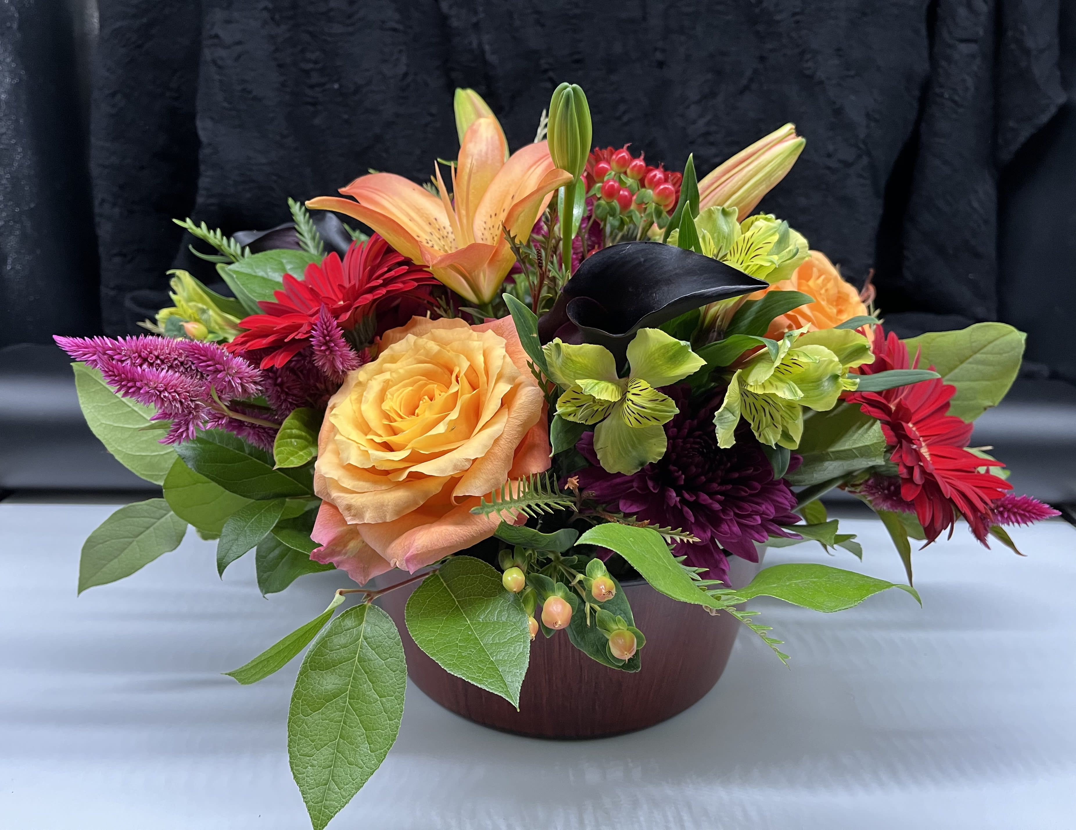 Harvest Centerpiece  - This  beautiful traditional table centerpiece is perfect to celebrate Autumn and Thanksgiving.  A seasonal assortment will be hand selected by our talented designers  creating a low round table centerpiece . Flower selection will vary according to availability . Designed in our low round glass  cylinder   approx. 12”wide   