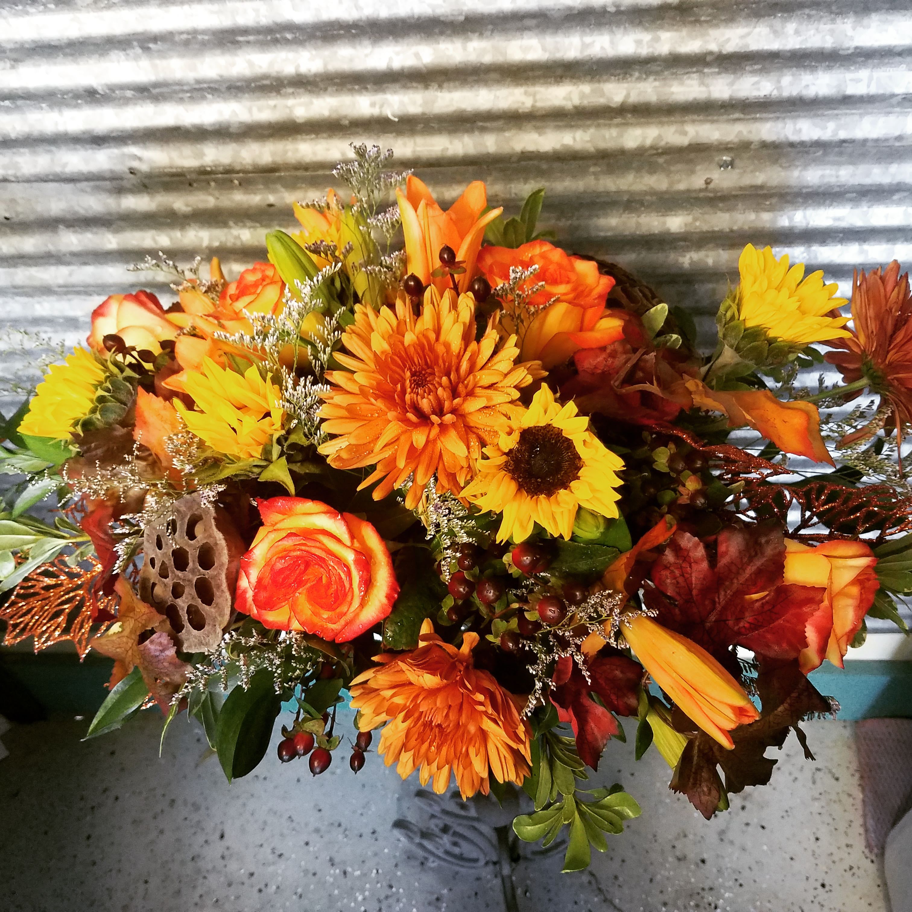 Rustic Harvest Glow arrangement - Celebrate the beauty of autumn with our Rustic Harvest Glow arrangement — a warm mix of orange roses, golden sunflowers, chrysanthemums, lilies, and seasonal foliage. Hand-designed with a natural, rustic charm, this bouquet brings the vibrant colors of fall to life. Perfect for Thanksgiving tables, home décor, or thoughtful gifts, each arrangement is crafted by your local Omaha area florist using the freshest blooms and textural accents like berries, pods, and fall leaves. Order online or call today before 12 noon central time for same-day flower delivery and let this stunning design fill your space with warmth and seasonal joy.