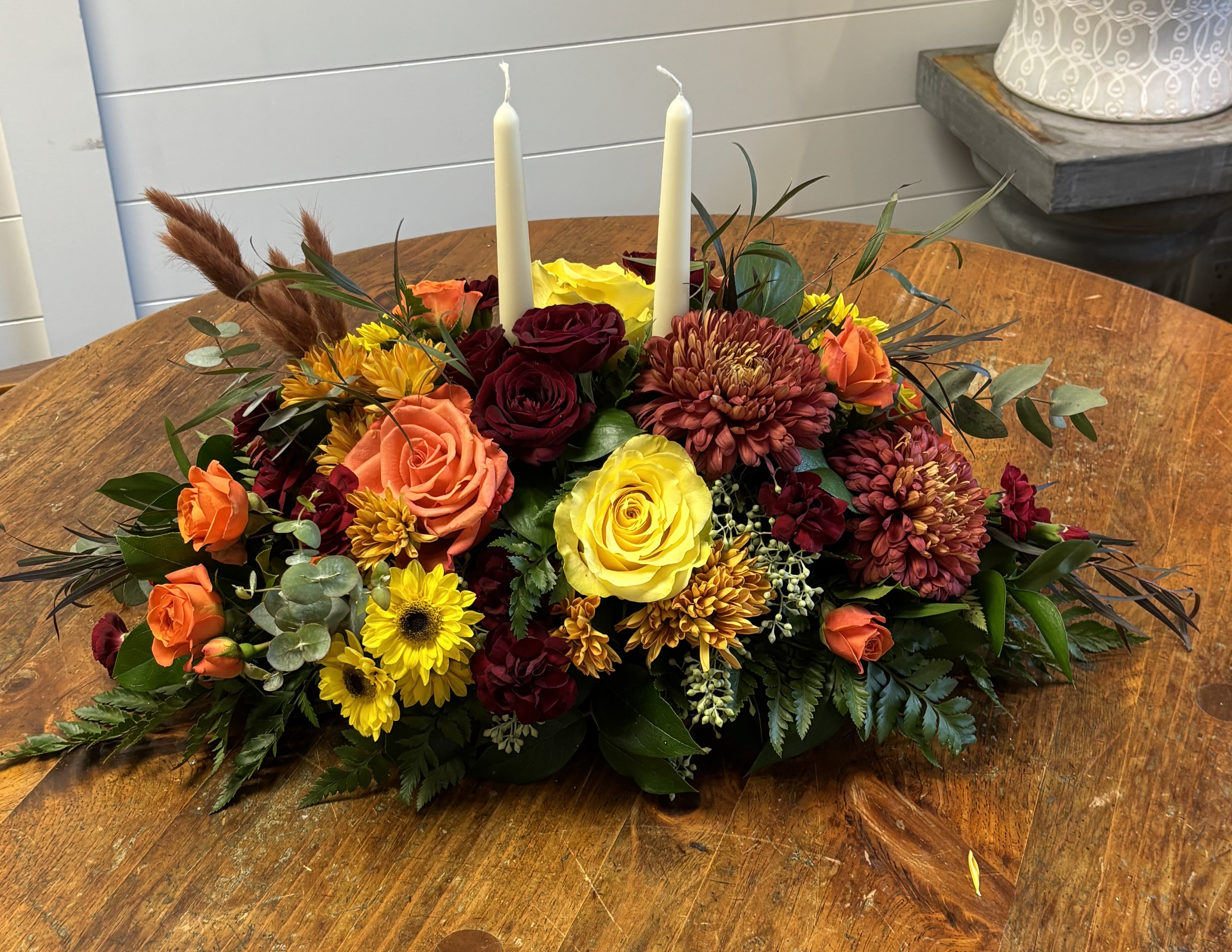 Elegant Traditions - This floral centerpiece is a long and low arrangement designed for a dining table. The arrangement is composed of a variety of flowers and foliage in warm autumnal colors, creating a rich and textured look ****flower variety may vary based on availability ****