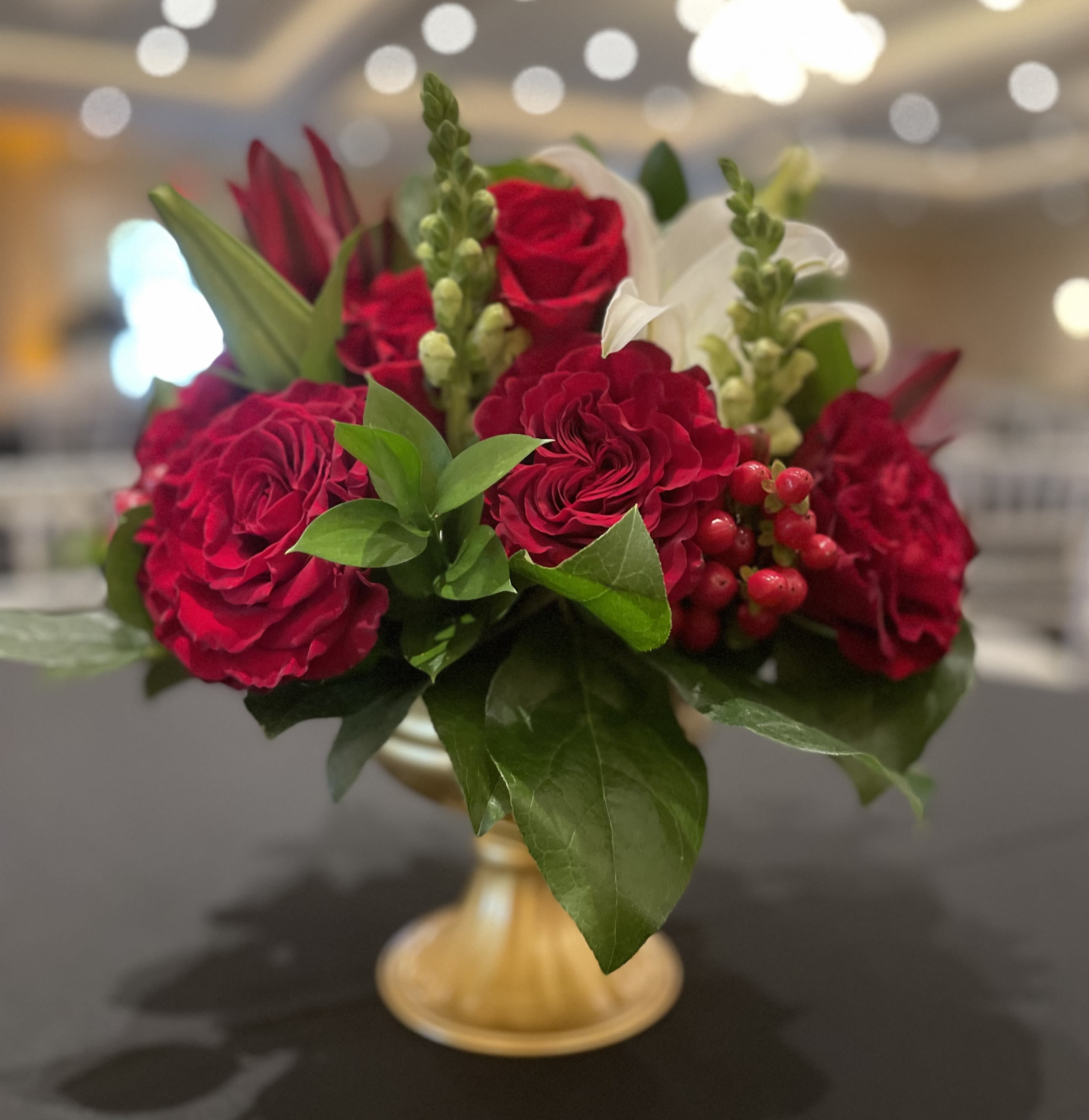 Christmas Delight - Christmas Delight – Elegant Holiday Flower Arrangement in Wilmington, Delaware  Make the season shine with Christmas Delight, a luxurious holiday floral arrangement handcrafted by your local Wilmington, Delaware florist. This elegant design features radiant white lilies, graceful white snapdragons, rich red heart roses, festive red hypericum berries, and lush seasonal greens, all beautifully arranged in a gleaming gold pedestal vase. Perfect as a Christmas centerpiece, holiday gift, or a stunning accent for your home or office, Christmas Delight captures the beauty and warmth of the holiday season. Each arrangement is carefully designed with premium, fresh flowers and is available for same-day flower delivery in Wilmington, DE, and surrounding areas. Order Christmas Delight today from your trusted Wilmington florist and celebrate the holidays with elegance, color, and festive charm.