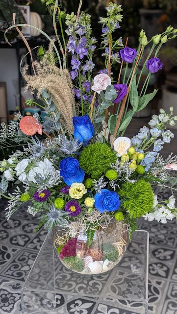 Life is a Beach (Designer Choice) - This arrangement is a designer choice. There is no guarantee of flowers especially the blue roses. If you have specifics you must order in advanced to see if we can get the flowers requested. Height and width will vary due to flowers being used. Scenery inside bowl will change due to what we have available.