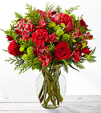 Christmas Tidings Bouquet - This bouquet blooms with the goodwill and cheer of the Christmas season to send your warmest wishes to your favorite friends, family, and co-workers! Rich red roses, red carnations, and red Peruvian Lilies are accented perfectly with bright green button poms and a collection of lush Christmas greens to create a stunning seasonal display. Presented in a clear glass vase, this gorgeous holiday flower arrangement is set to make a heart-warming holiday gift!
