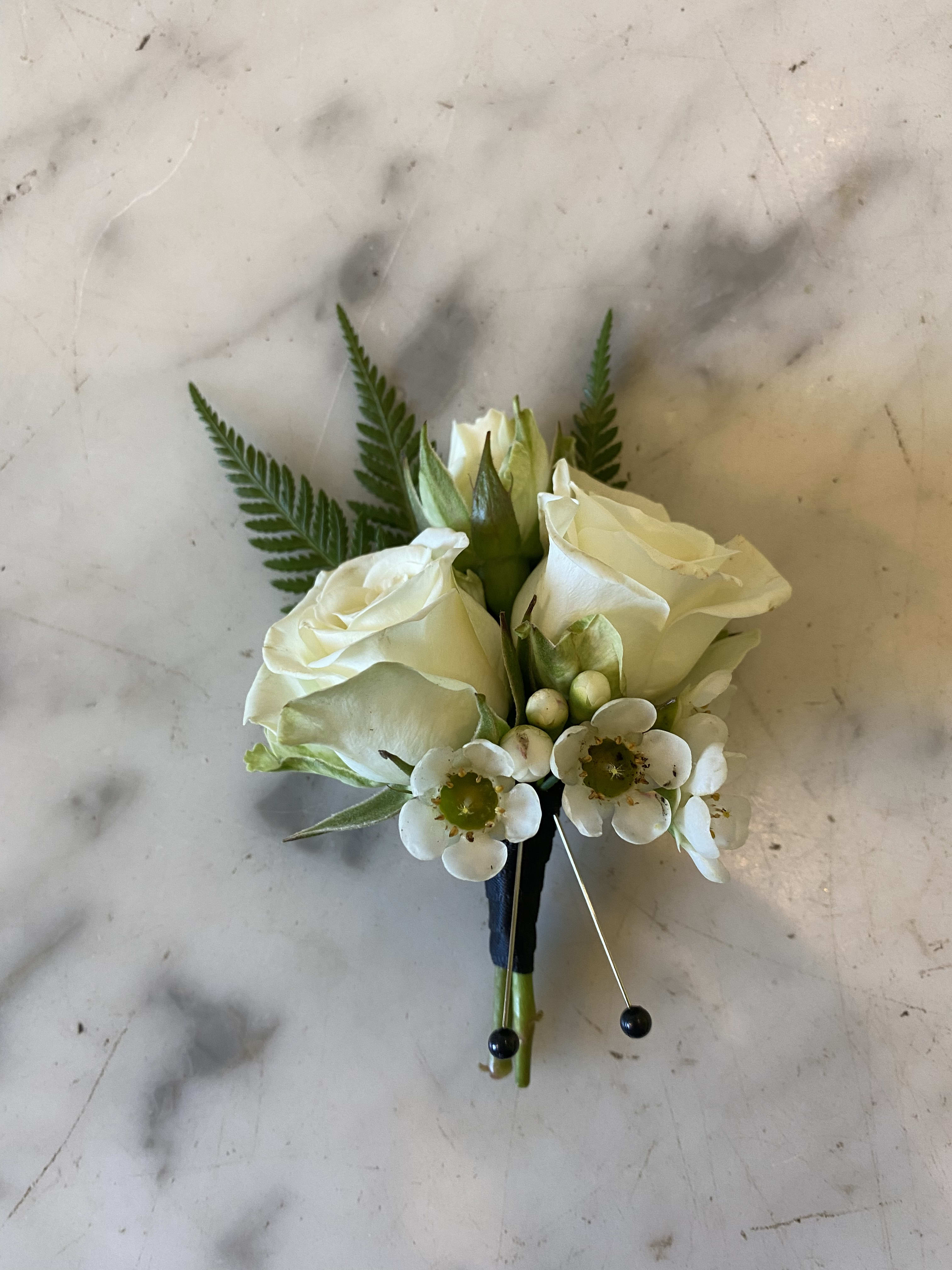 Urban Gardener Boutonnière  - Classic white spray rose boutonnière accented with filler and greenery tied with black ribbon. 