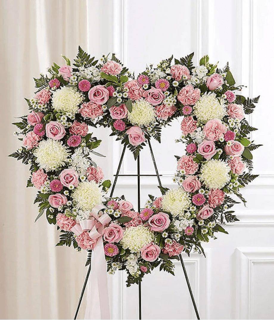 Pink &amp; White Standing Open Heart - Convey your deepest condolences and undying love with this beautiful arrangement. Pink and white flowers such as roses, stock, and carnations are arranged in an open heart and sent directly to the funeral home by family and friends. We use only the freshest flowers available so components may vary. &nbsp;Send your condolences with the Pink &amp; White Heart Wreath today.The wreath measures approximately 34&quot;H x 32&quot;L.  Includes:&nbsp; • Pink Roses&nbsp; • Pink Carnations&nbsp; • Pink Asters&nbsp; • White Mums&nbsp; • White Stock&nbsp; • Baby's Breath&nbsp; • Open Heart Standing Spray