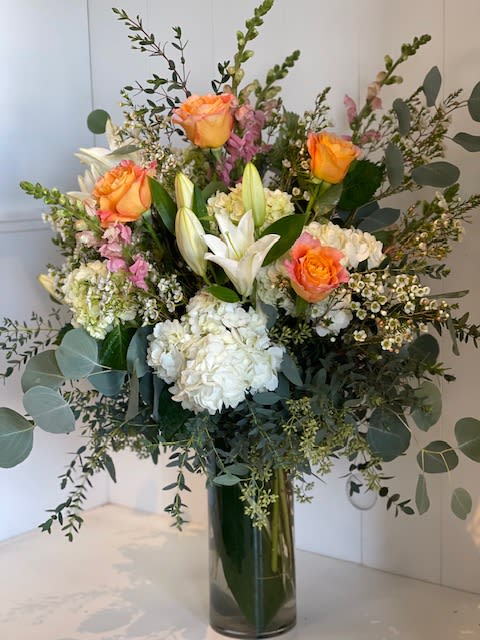 Always Pretty - A stunning tall and airy design featuring a blend of white and green hydrangeas, pristine white lilies, delicate snapdragons, and bright-colored roses (subject to store availability). Accented with rustic foliage and arranged in a sleek tall cylinder vase, this arrangement offers a perfect balance of freshness and sophistication, ideal for any occasion.