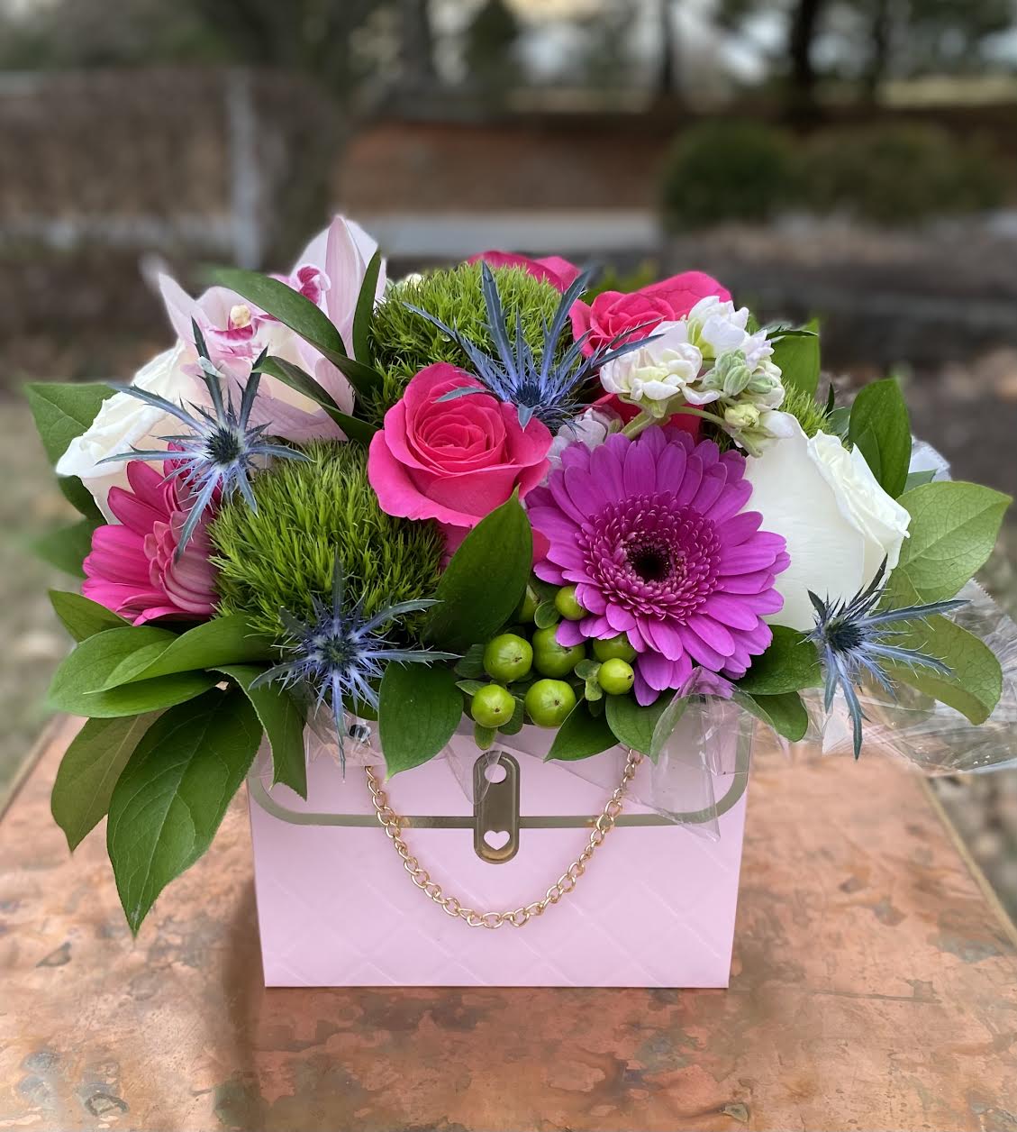 Pink Mini Purse - Pink Mini Purse – Fun &amp; Stylish Pink Floral Arrangement | Wilmington, Delaware Local Florist  Add a playful touch of elegance with the Pink Mini Purse, a unique and vibrant floral design handcrafted by your trusted Wilmington, Delaware florist. This eye-catching arrangement features fresh green trichelium, bold hot pink Gerber daisies, hot pink roses, classic white roses, a delicate pink orchid, and green hypericum berries. All blooms are artfully arranged in a charming pink purse-shaped container, making this design as fun as it is beautiful.  Perfect for birthdays, sweet surprises, celebrations, or just because. Available for same-day flower delivery in Wilmington, DE and surrounding areas. Count on our local flower shop for premium flowers, creative designs, and exceptional service.