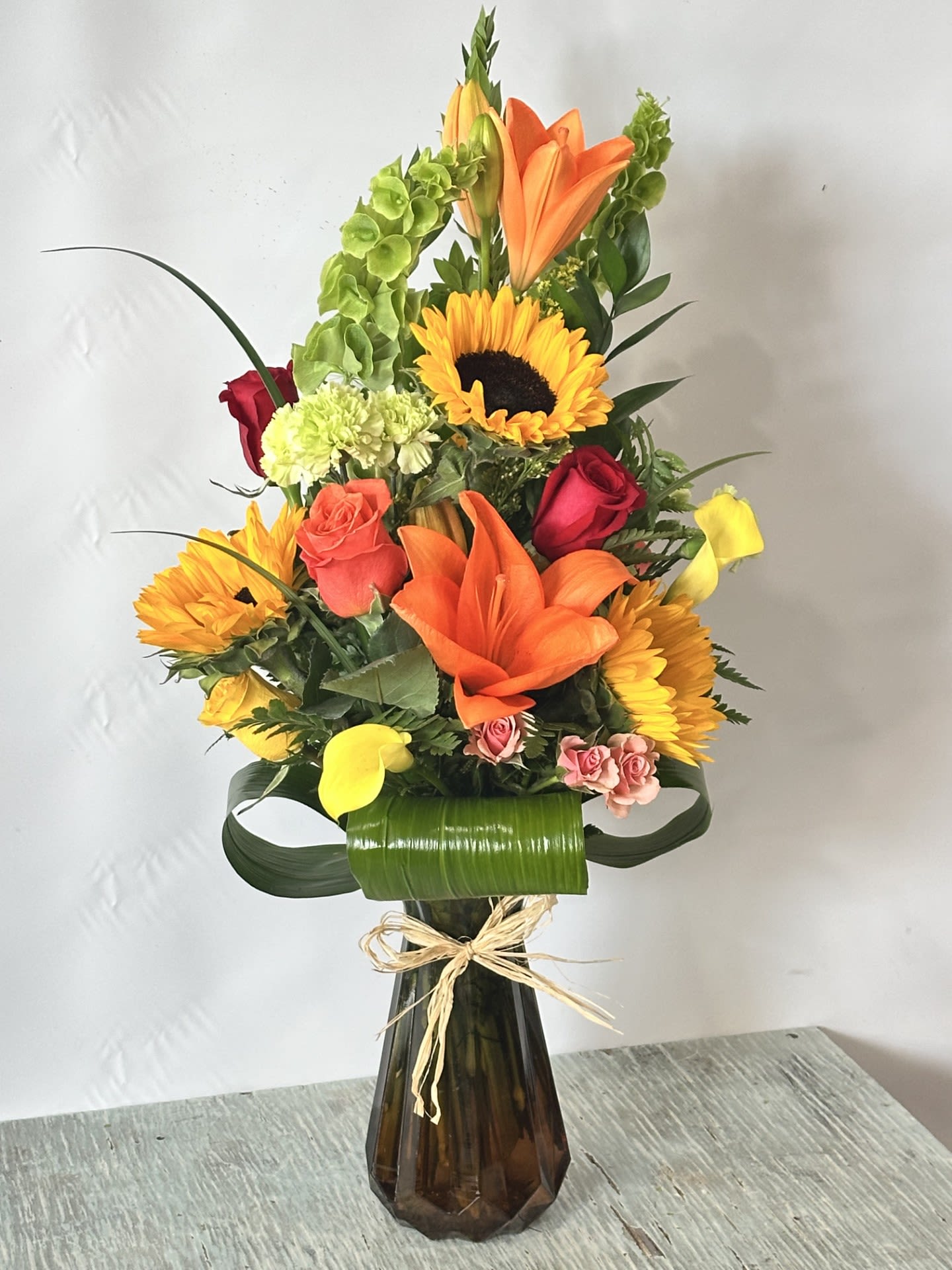 Autumn #4 - Fall colored arrangement designed in a ombre translucent vase. Top is green and bottom is brown.SAME DAY DELIVERY Please keep in mind we will try our best to make arrangement as similar as possible based on availability if a flower must be substituted we will keep arrangement within the same color scheme. 